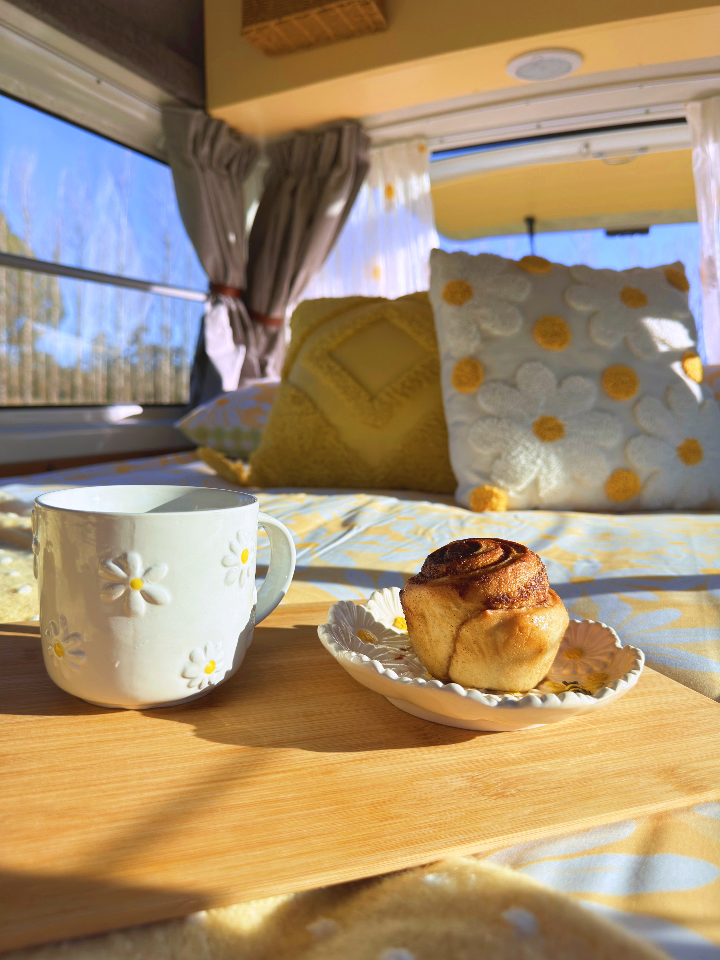 Cozy morning in an RV rental! Daisy mug, cinnamon roll, and sun-drenched pillows make for a perfect start to the day.. Toyota Hiace 2013