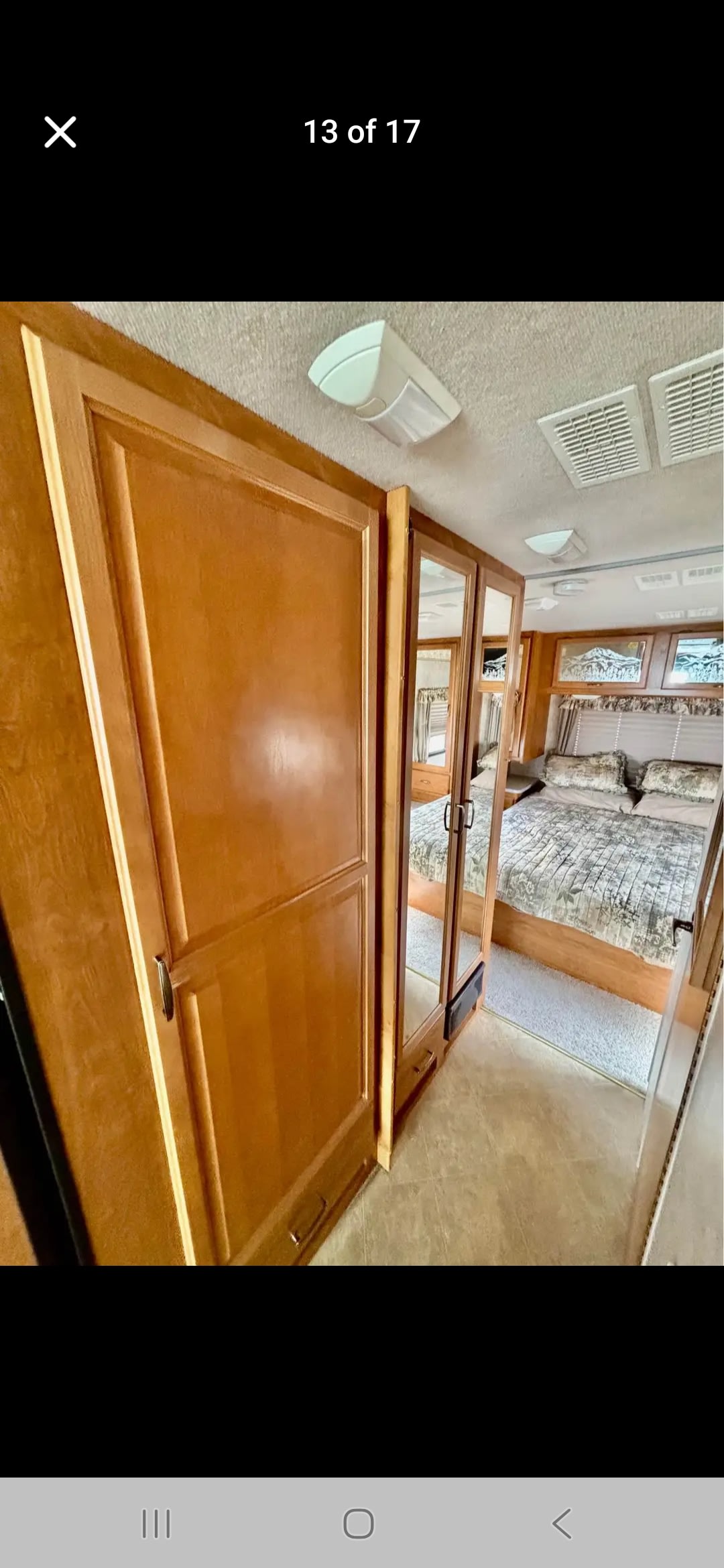 RV rental bedroom: Mirrored closet doors reveal a large bed, with ample wooden storage and ceiling vents.. Fleetwood Terra 2006