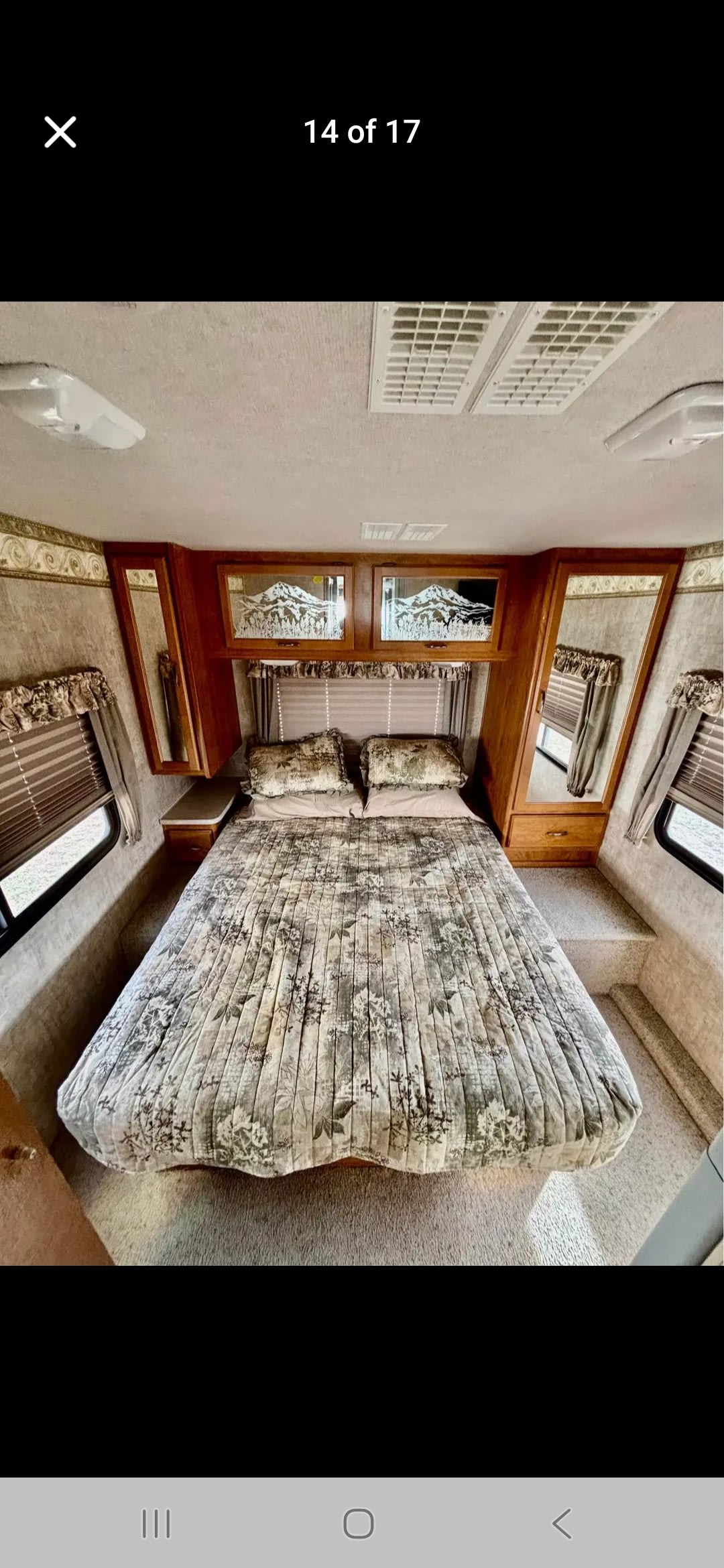 RV rental bedroom with nature-themed queen bed, overhead mountain-design cabinets, and mirrored wardrobes. Cozy space.. Fleetwood Terra 2006