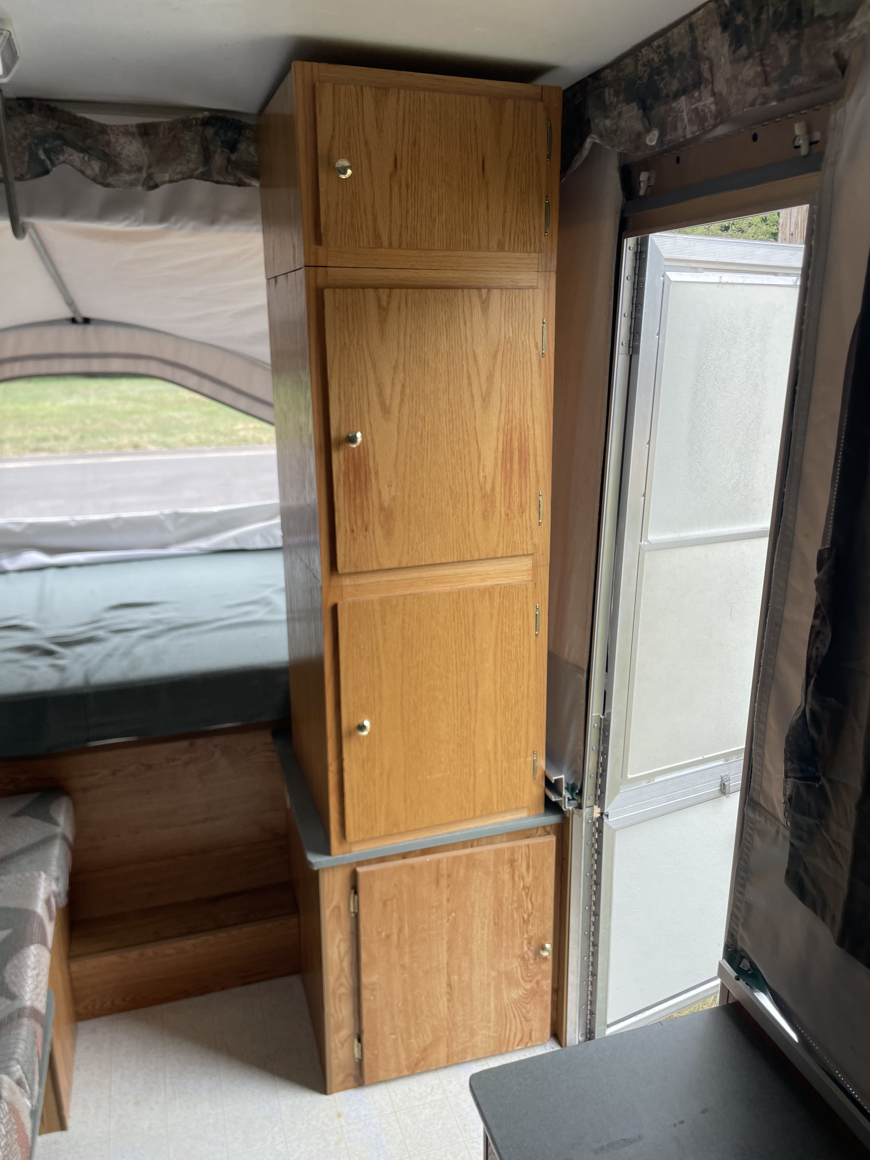 RV rental interior showing tall wooden cabinets, a bed area, and an open door revealing the outdoors.. Viking Epic 2000