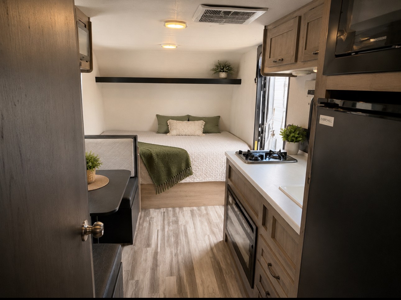 Cozy RV rental interior featuring a compact bedroom, dinette, and kitchen with a stovetop, sink, and refrigerator.. Cruiser RV Avenir 2025
