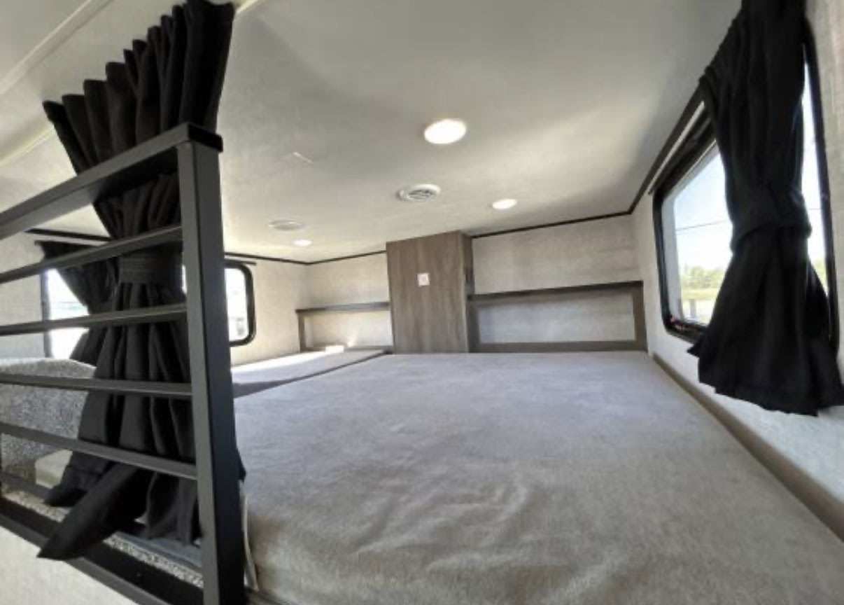 Cozy rv rental bunk beds: featuring black curtains, shelves, and bright lighting, offering a comfortable sleeping space for travelers.. Jayco Jay Flight Bungalow 2025