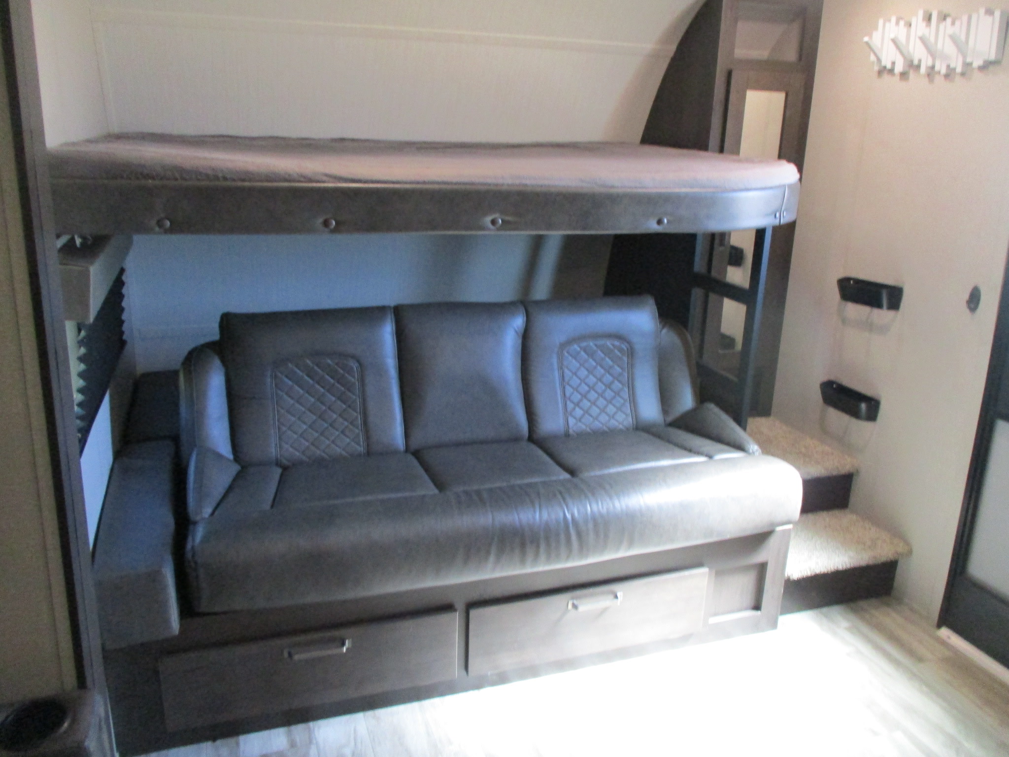 RV rental interior featuring a bunk bed over a versatile sofa bed, complete with storage drawers and steps.. Grand Design Transcend Xplor 2022