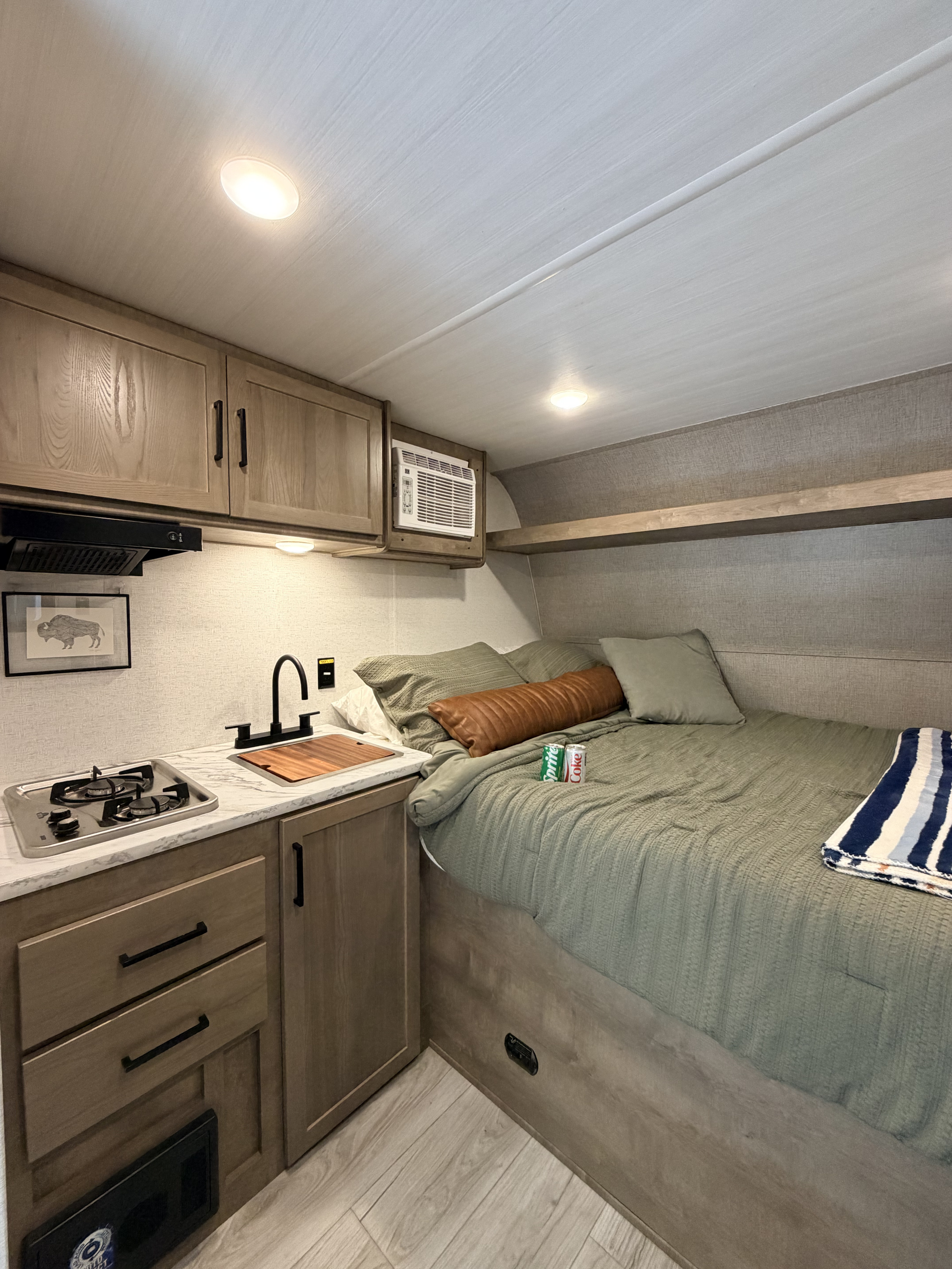 Modern rv rental interior featuring a compact kitchen, comfortable bed, and an AC unit for cozy travel.. Keystone RV Springdale Mini 2025