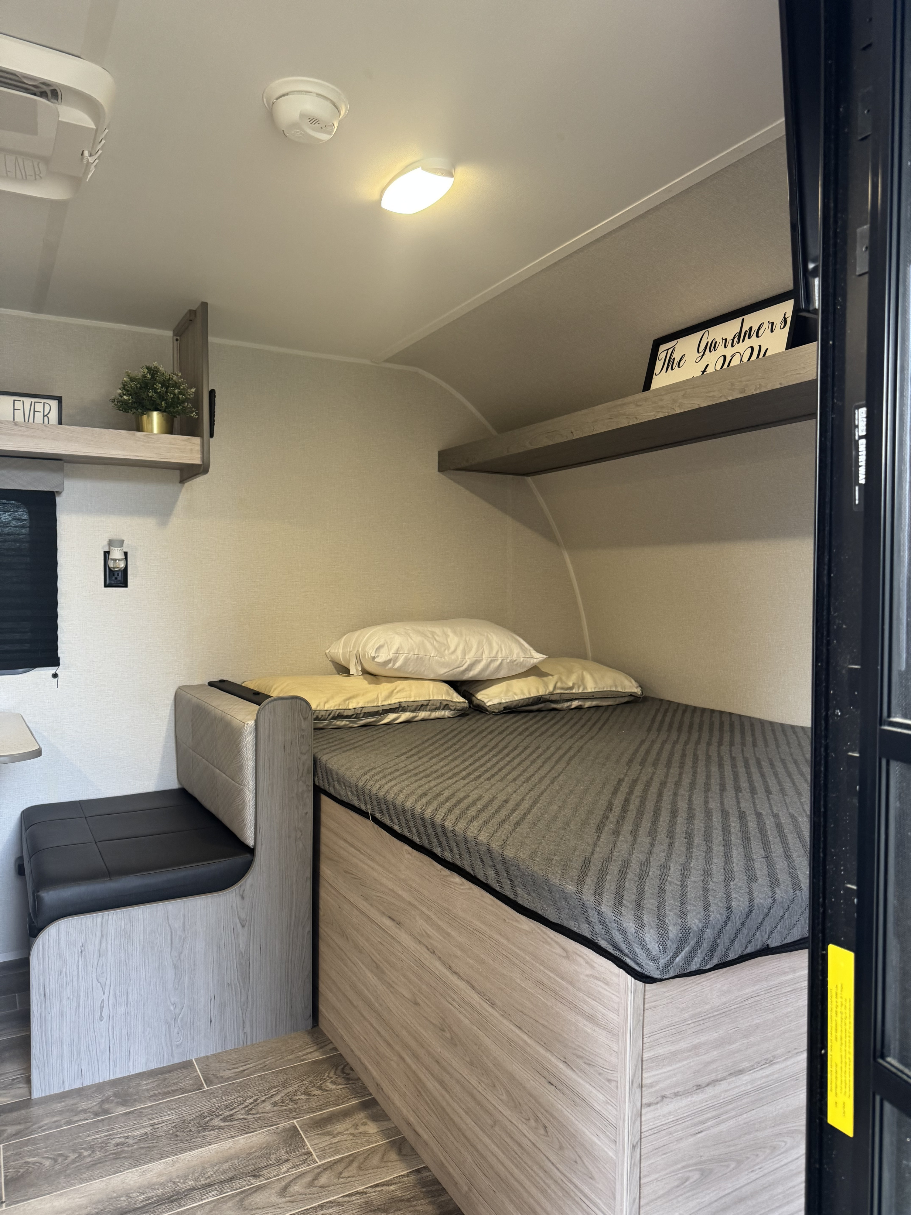 Cozy RV rental interior with a comfortable bed, dinette seating, and modern wood-look finishes, perfect for travel.. Heartland RVs Pioneer 2025