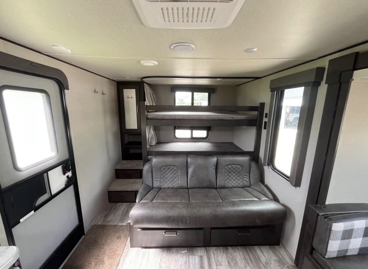 Spacious RV rental interior featuring bunk beds, a convertible sofa, and ample living space, ideal for family adventures.. Grand Design Transcend Xplor 2022