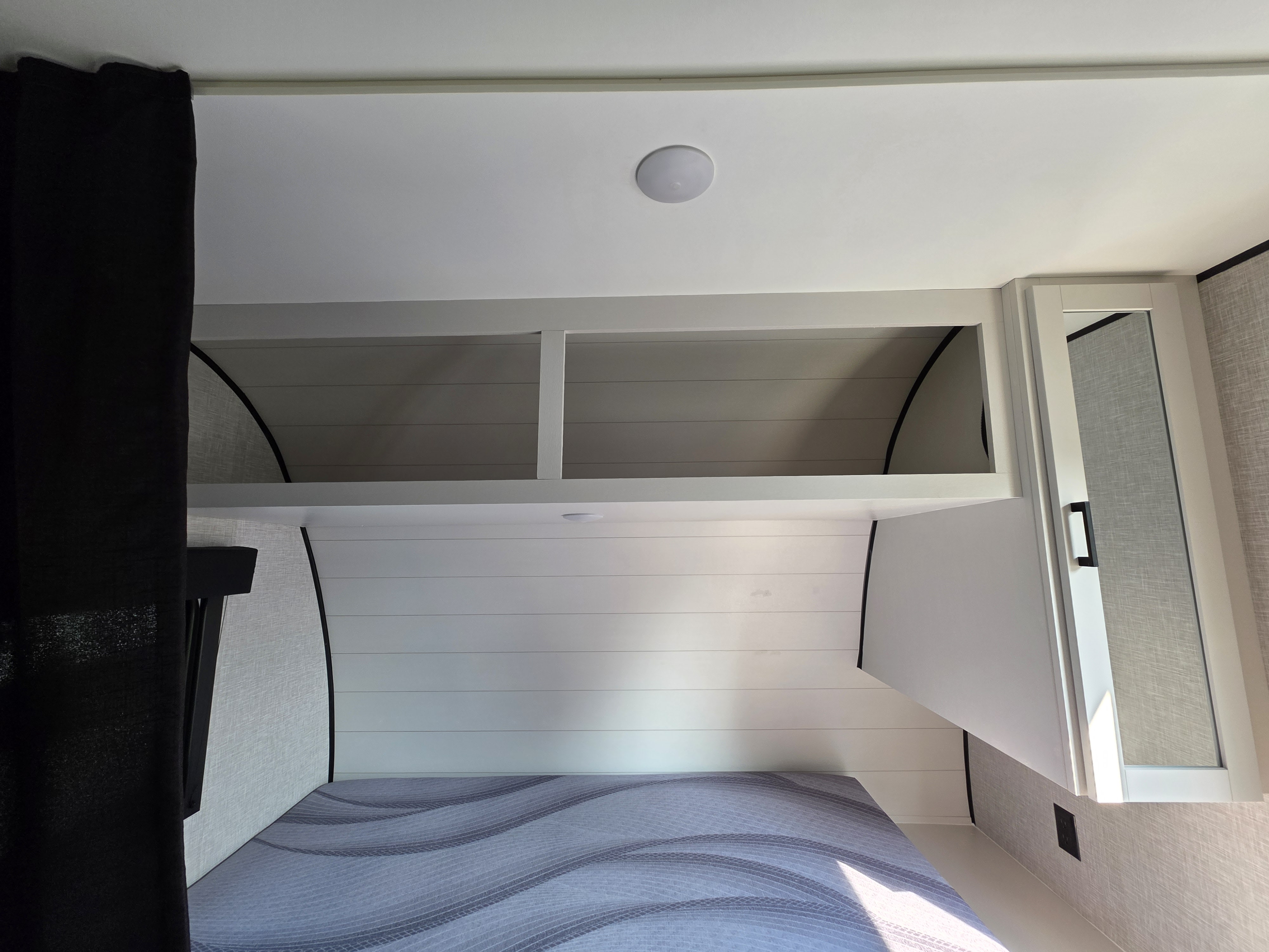 RV rental: Bright bedroom with patterned bed, shiplap wall, open overhead storage, and mirrored cabinet.. Starcraft Autumn Ridge 2025
