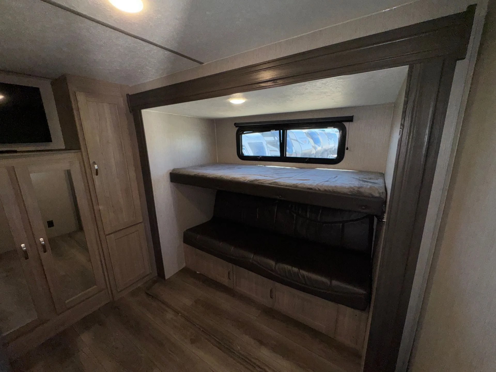 This RV rental interior features a bunk bed over a couch, with a wardrobe and TV visible left. A cozy space for travelers.. Coachmen Freedom Express 320BHDSLE 2021