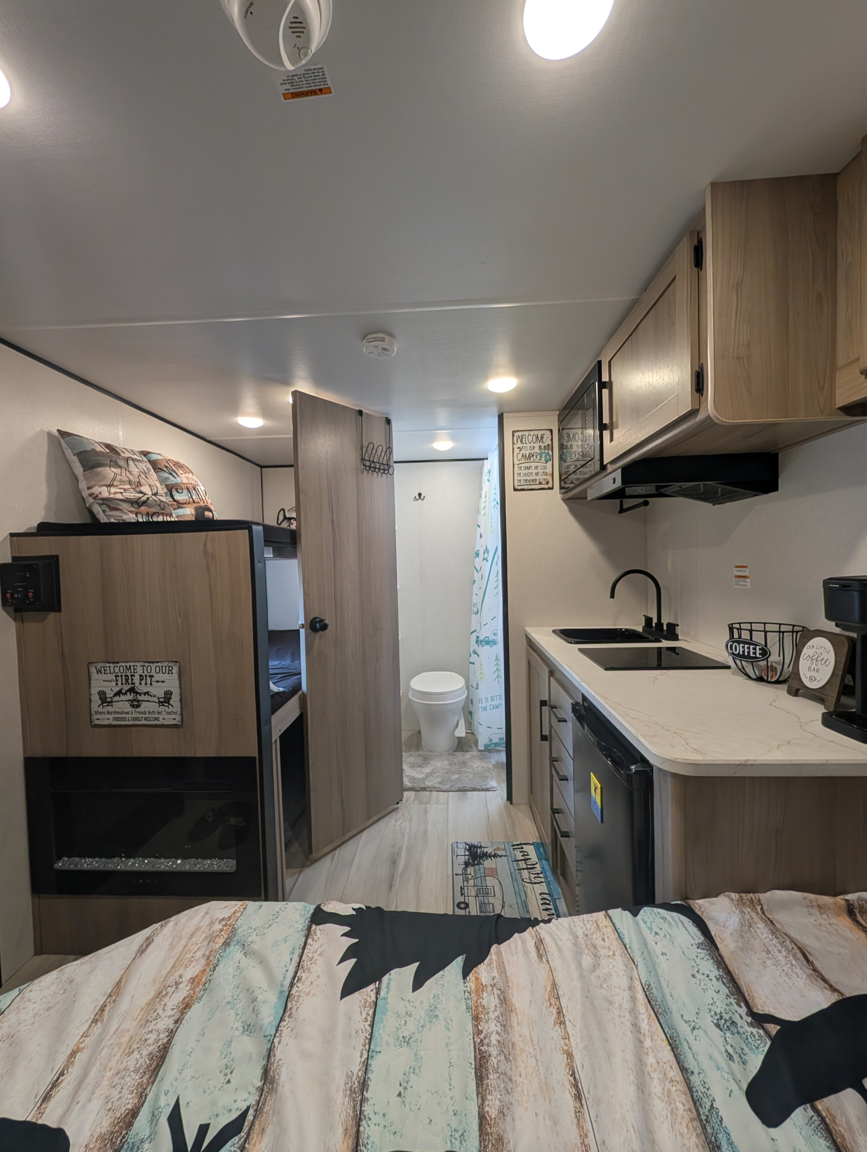 Step inside this RV rental, featuring a compact kitchen, bathroom, bunk beds, and a cozy fireplace.. Keystone RV Coleman 2025