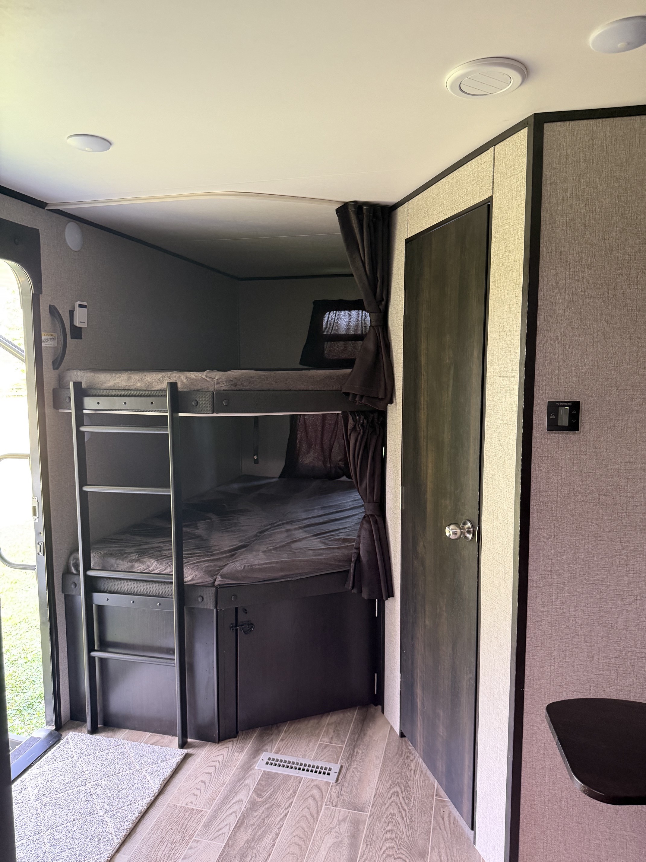 RV rental interior features bunk beds with a ladder, privacy curtains, and a wall-mounted control panel.. Jayco Jay Flight 2021
