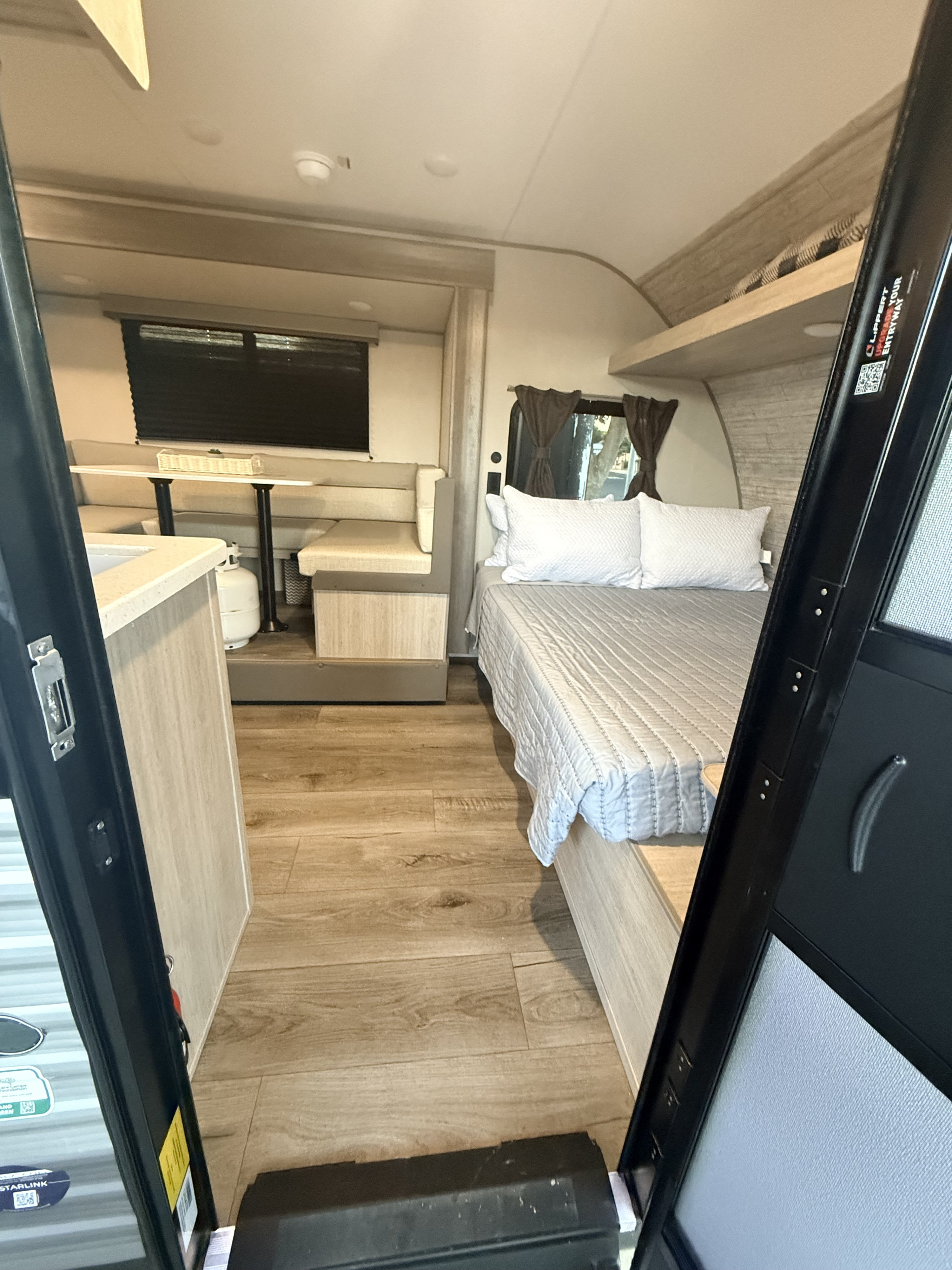 This RV rental interior features a cozy bed, dinette with a table, and a small kitchen counter, offering comfortable living on the road.. Forest River Summit series 7 2026