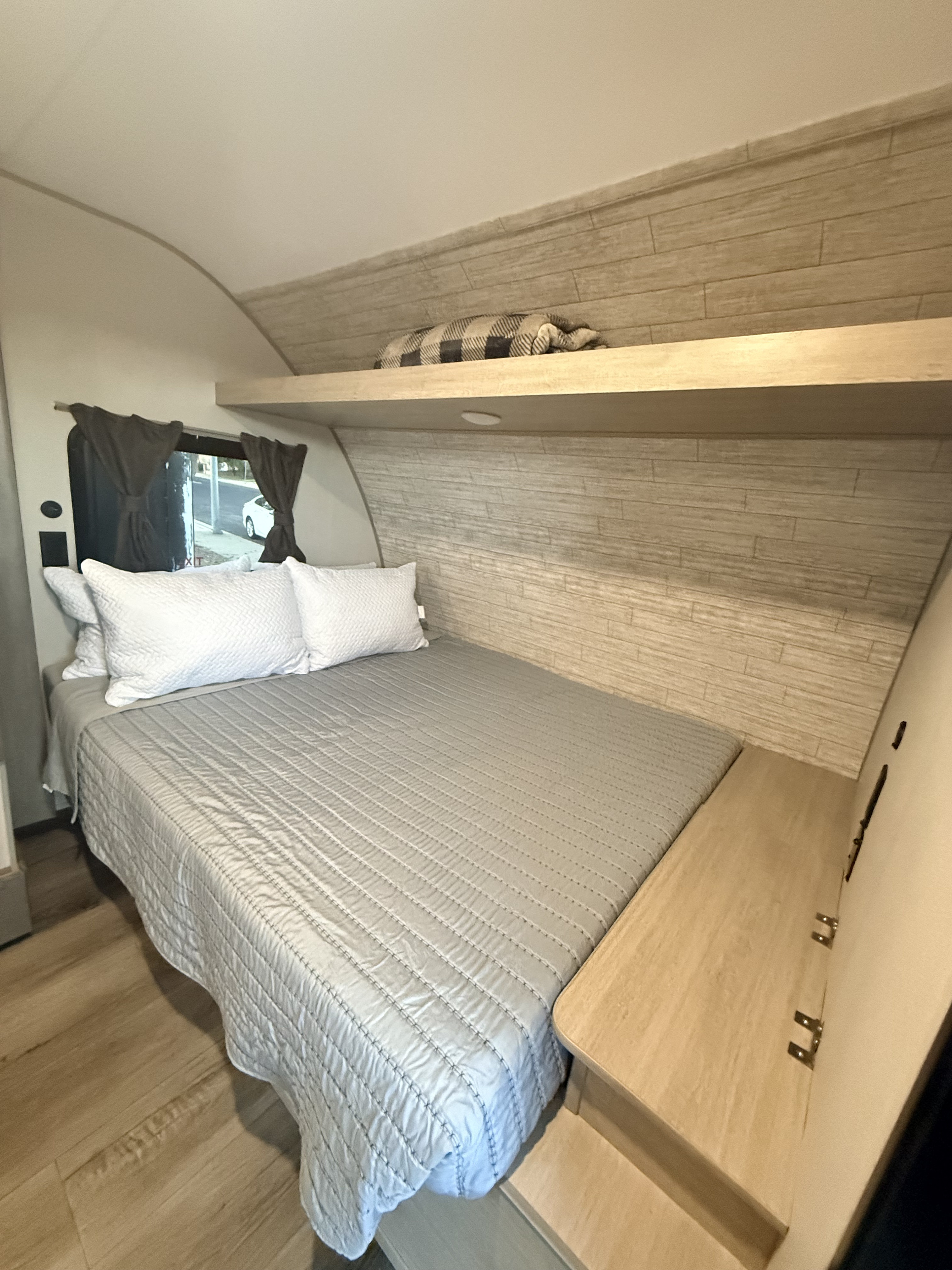 Cozy RV rental bedroom with a comfy bed, light wood accents, overhead shelf, and a window for comfortable travels.. Forest River Summit series 7 2026
