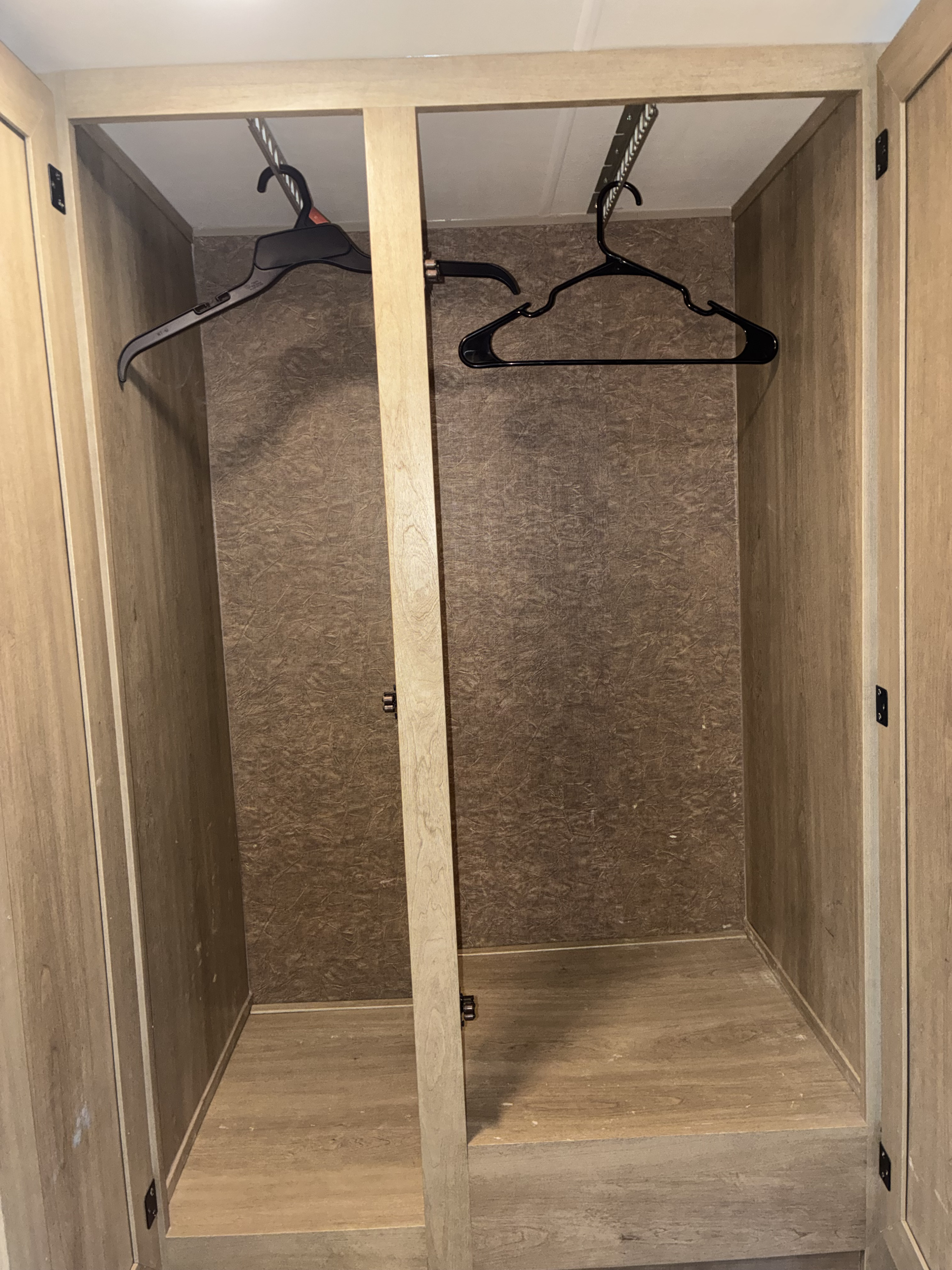 Empty wooden RV rental closet with two sections and hanging rods, perfect for packing clothes.. Forest River Coachmen Freelander 2015