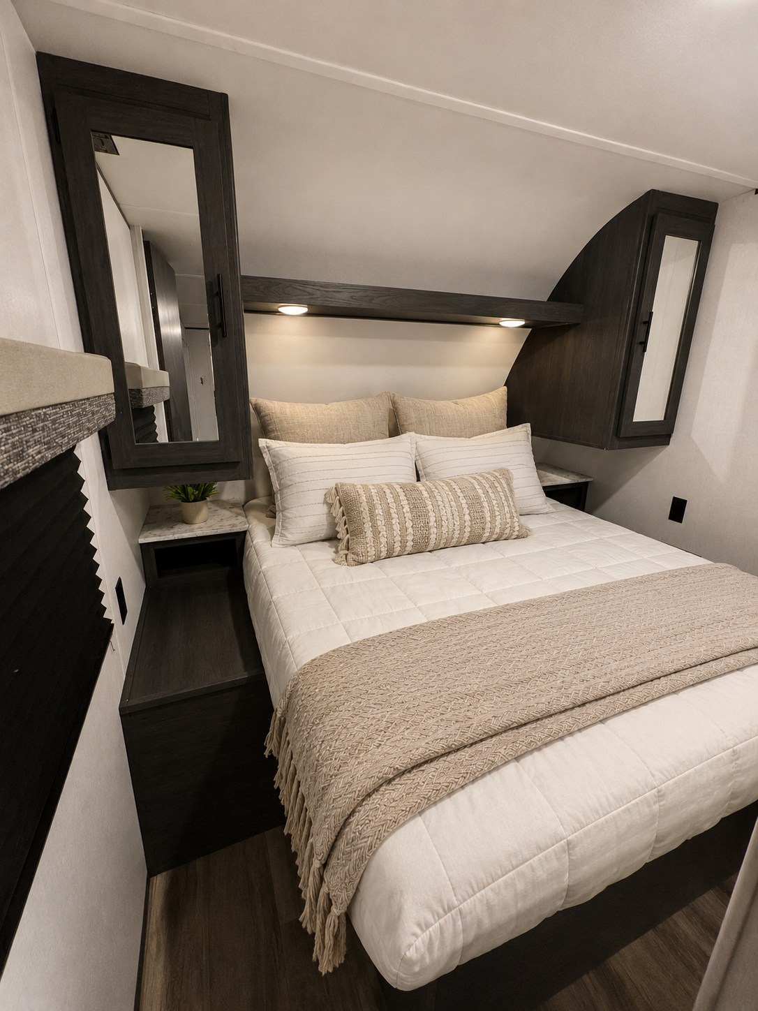 Cozy RV rental bedroom with modern dark wood cabinets, comfy queen bed, soft lighting, and warm textiles. Perfect for travel.. Dutchmen Colorado 2024
