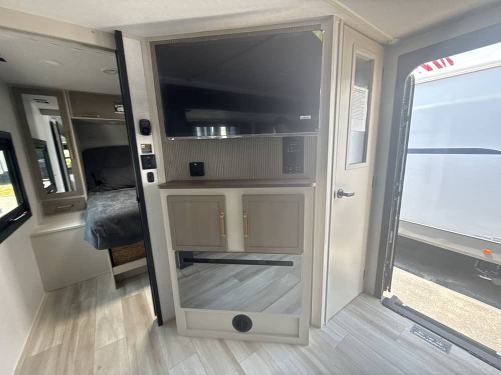 Modern RV rental interior with TV entertainment, stylish storage, and a glimpse into the cozy bedroom area.. Forest River Salem Hemisphere HL 2025