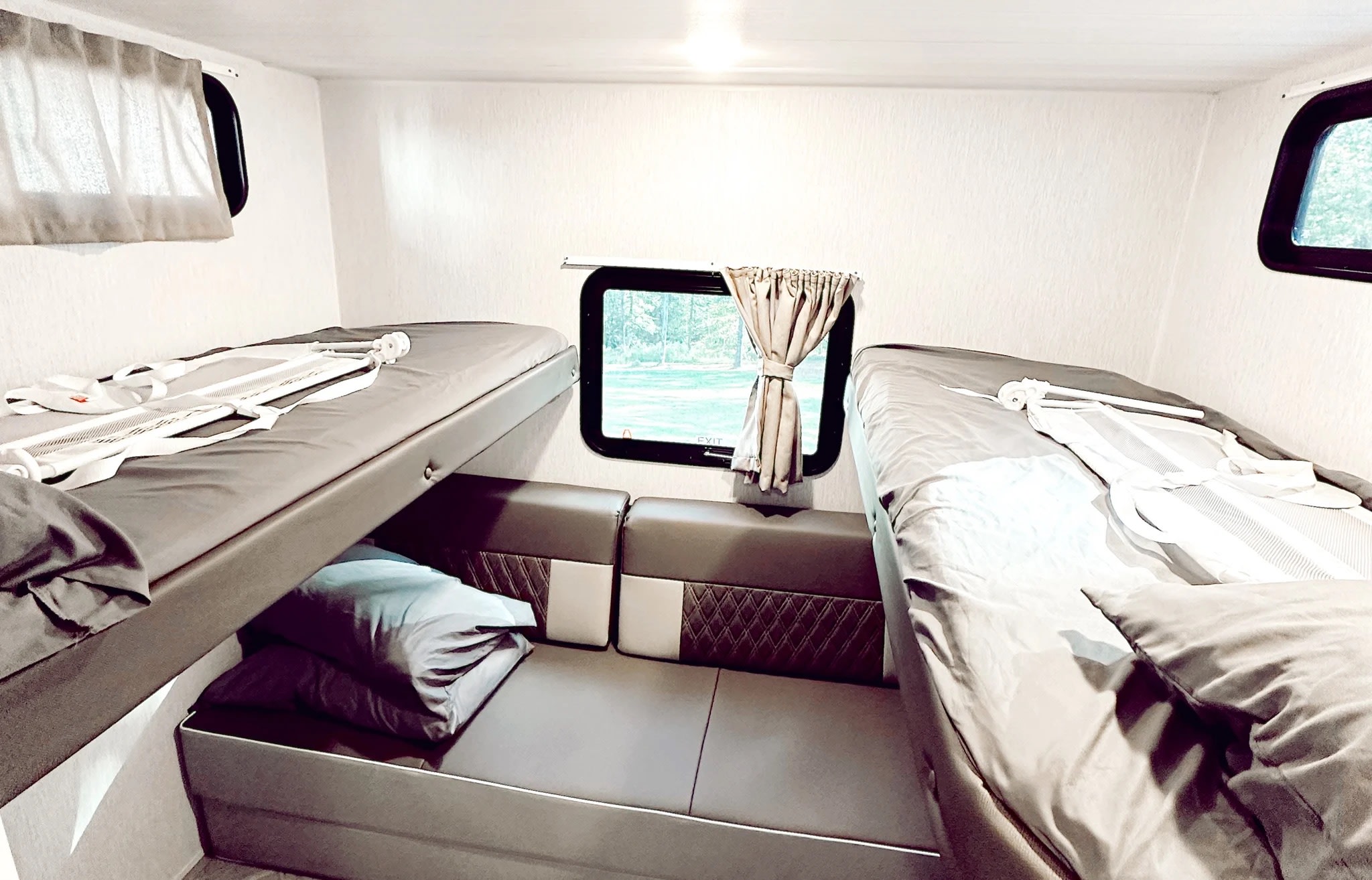 RV rental interior: a bright, clean space featuring bunk beds with safety straps & a lower seating area/bed.. Forest River Wildwood X-Lite Platinum 2024