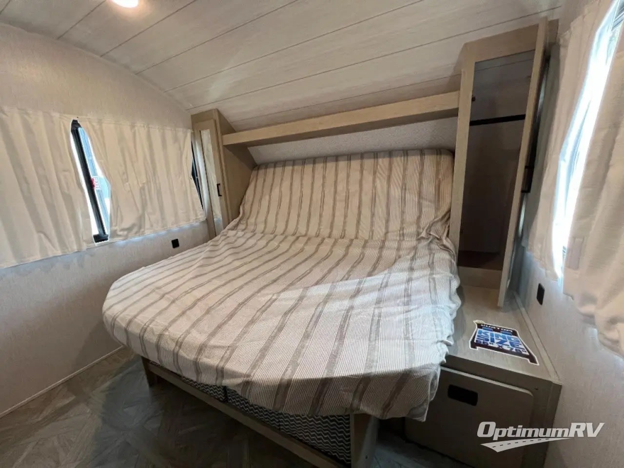 Cozy RV rental bedroom with a comfy bed, striped linens, windows, and built-in storage, perfect for travel.. Forest River Wildwood X-Lite Platinum 2024