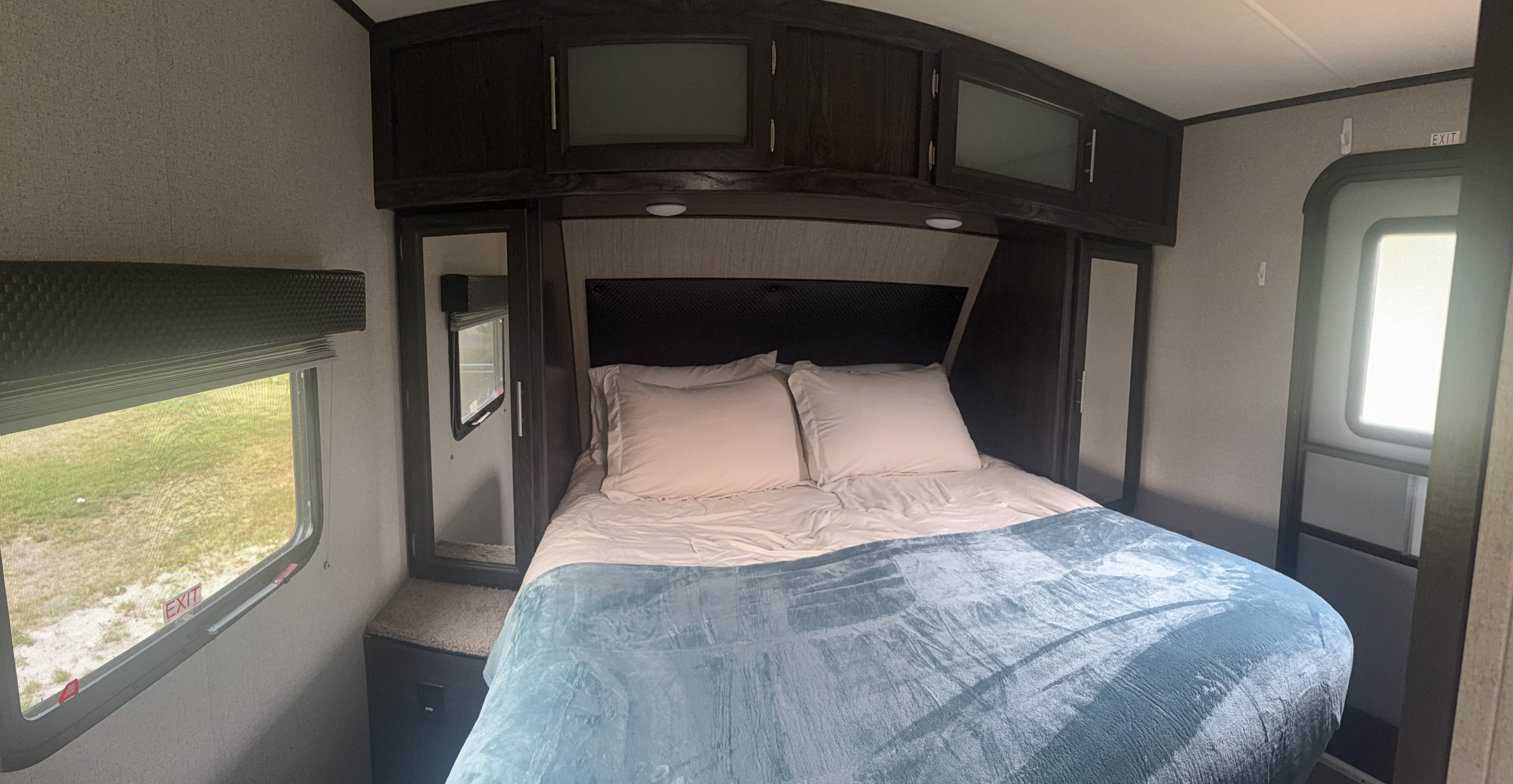 Cozy RV rental bedroom with a comfy bed, dark overhead cabinets, and windows, ideal for travel.. Kodiak Ultimate 288BHSL 2018