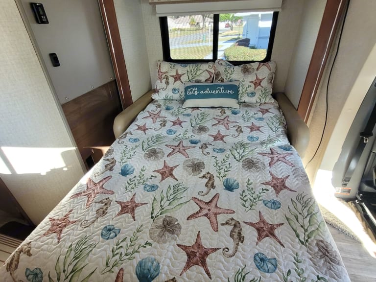 RV rental bed with a cozy marine-themed quilt, featuring starfish and seahorses. Perfect for your adventure!. Winnebago View 2017