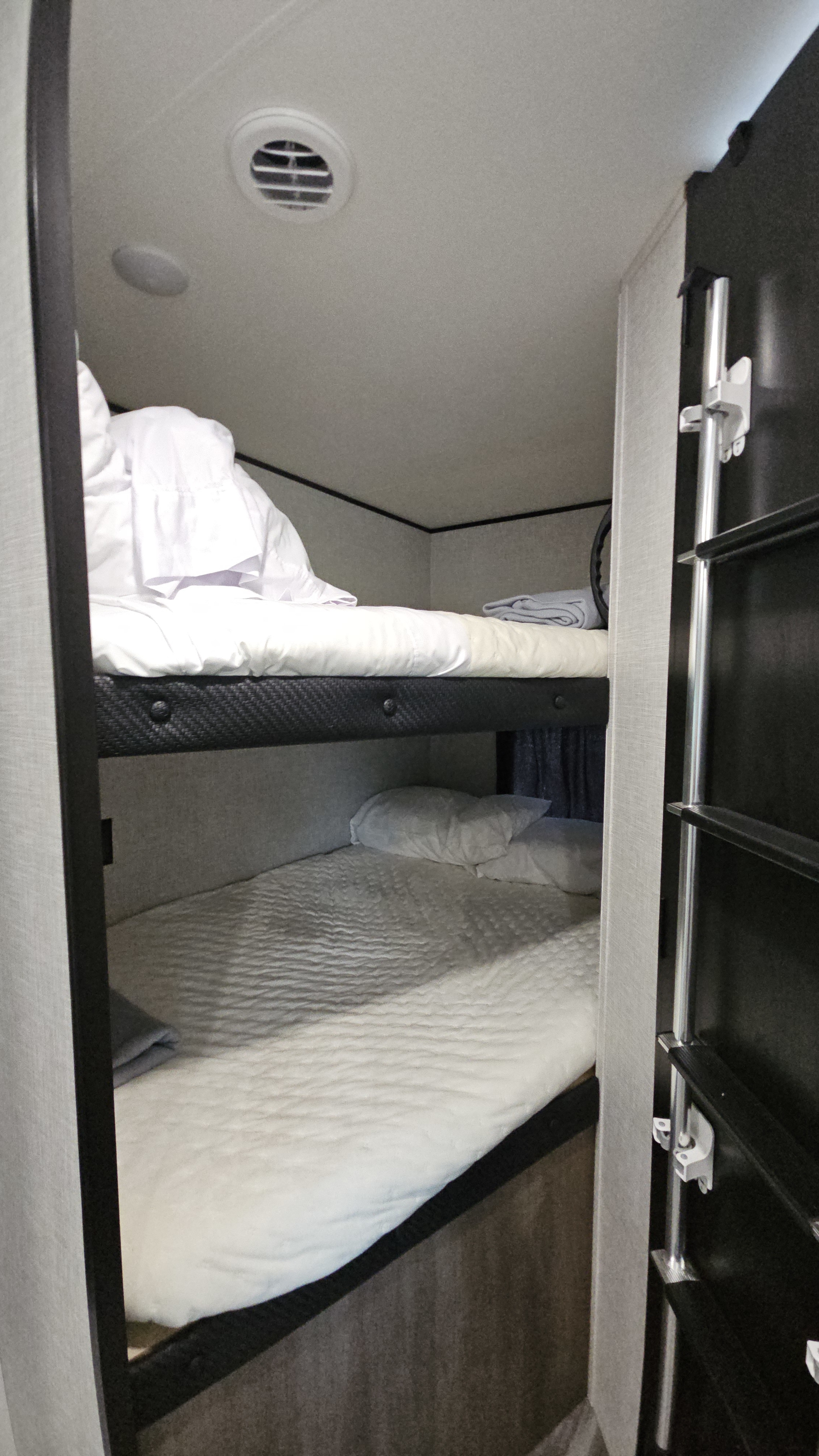 Cozy bunk beds in an RV rental, featuring stacked sleeping with white bedding, a pillow, and a side ladder.. Jayco Jay Flight SLX 2025