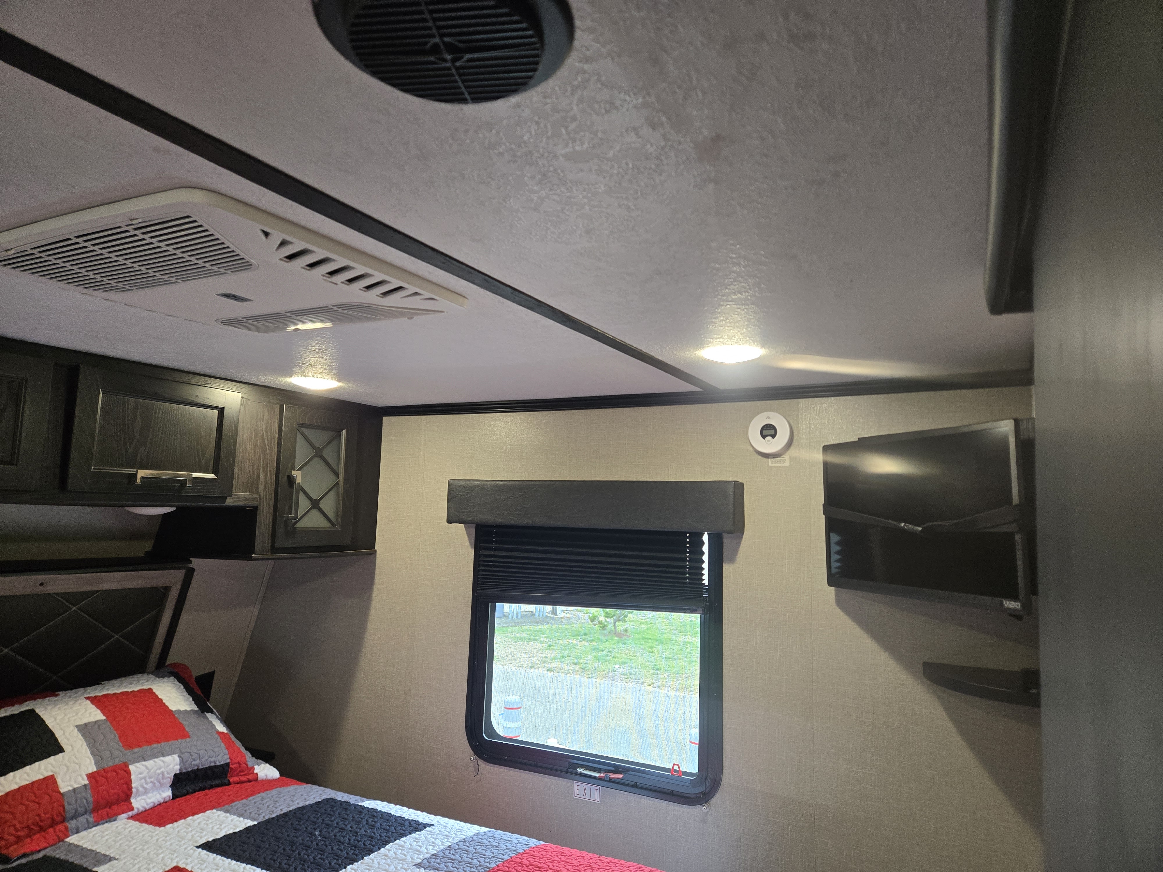 This RV rental features a compact bedroom with a bed, AC, TV, window, and storage cabinets, providing comfort on the go.. Keystone Fuzion 2018