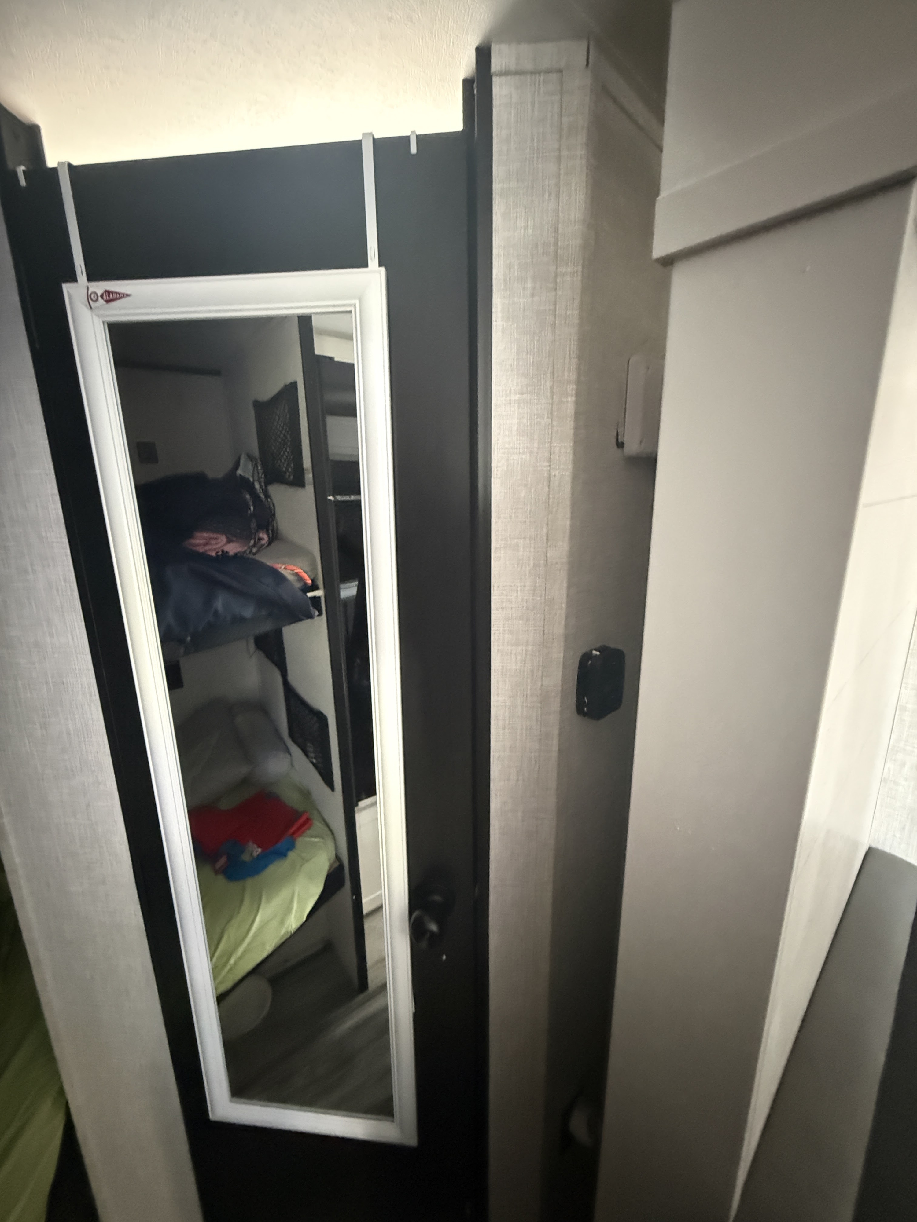 RV rental interior: bunk beds with bedding reflected in a mirror on a dark panel. An Alabama pennant hangs above the mirror.. Jayco Jay Flight SLX 2025
