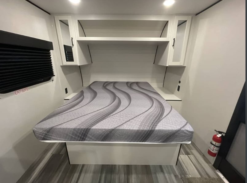 Clean rv rental bedroom with grey patterned mattress, overhead cabinets, and side shelves, ensuring a comfortable stay.. Jayco Jay Flight SLX Sport Edition 2026