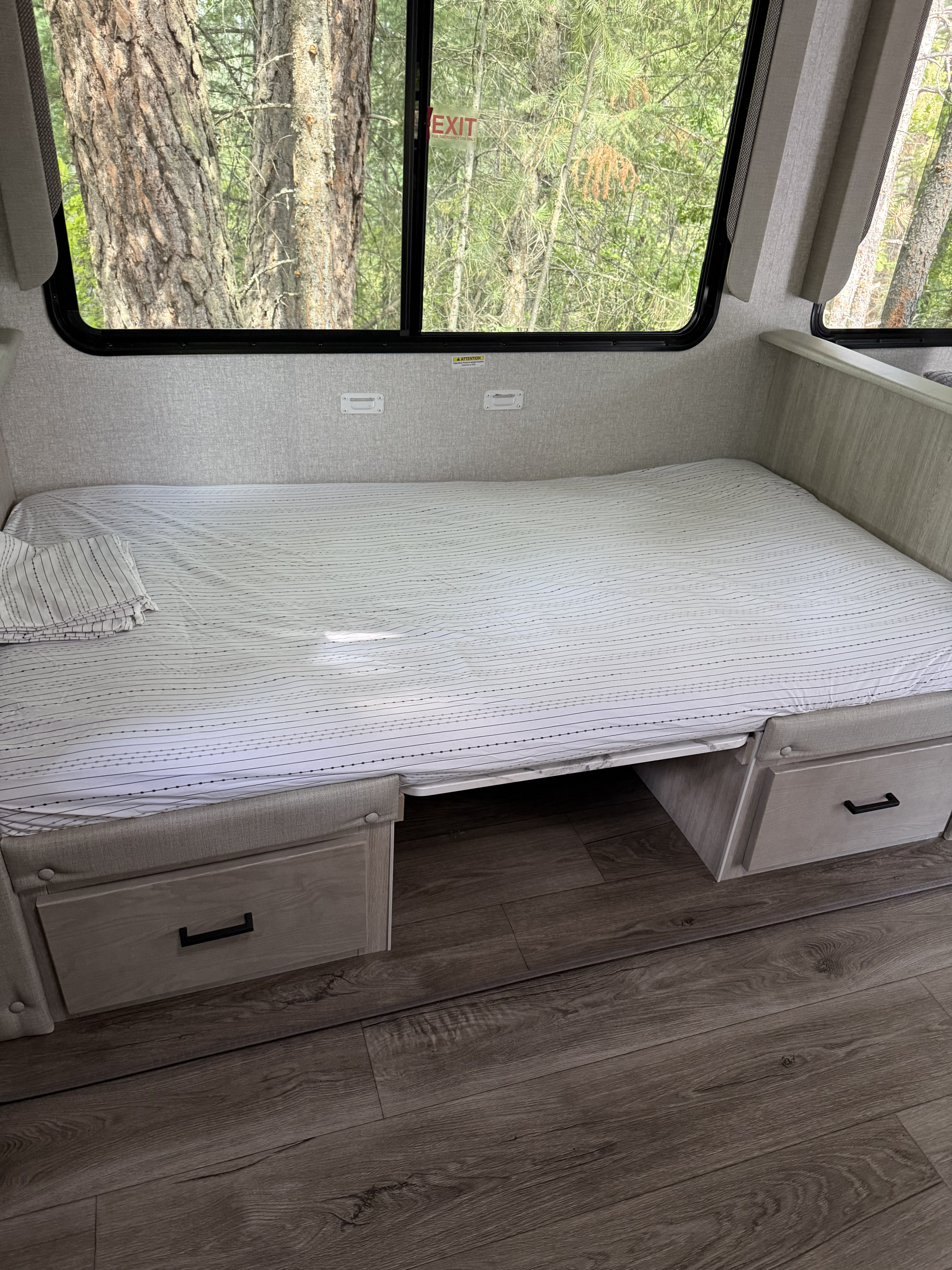 RV rental interior: Comfortable bed with under-bed storage drawers, and scenic forest views through wide windows.. Forest River 2810KIK 2022
