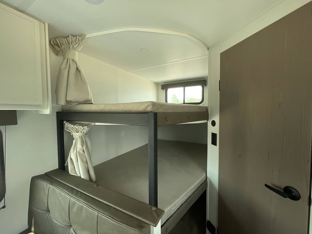 Cozy RV rental bunk beds, perfect for family adventures. Inside view of camper interior with sleeping arrangements.. Grand Design Transcend Xplor 2026