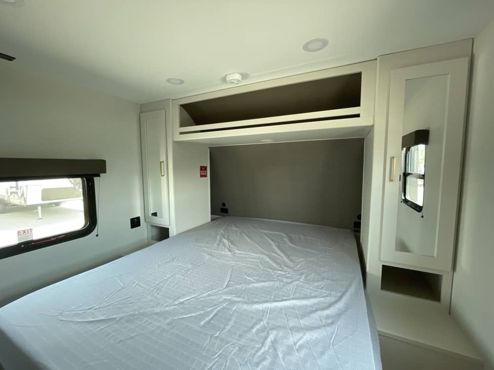 Modern RV rental bedroom features a comfy bed, integrated storage, and overhead cabinets for a functional space.. Grand Design Transcend Xplor 2026