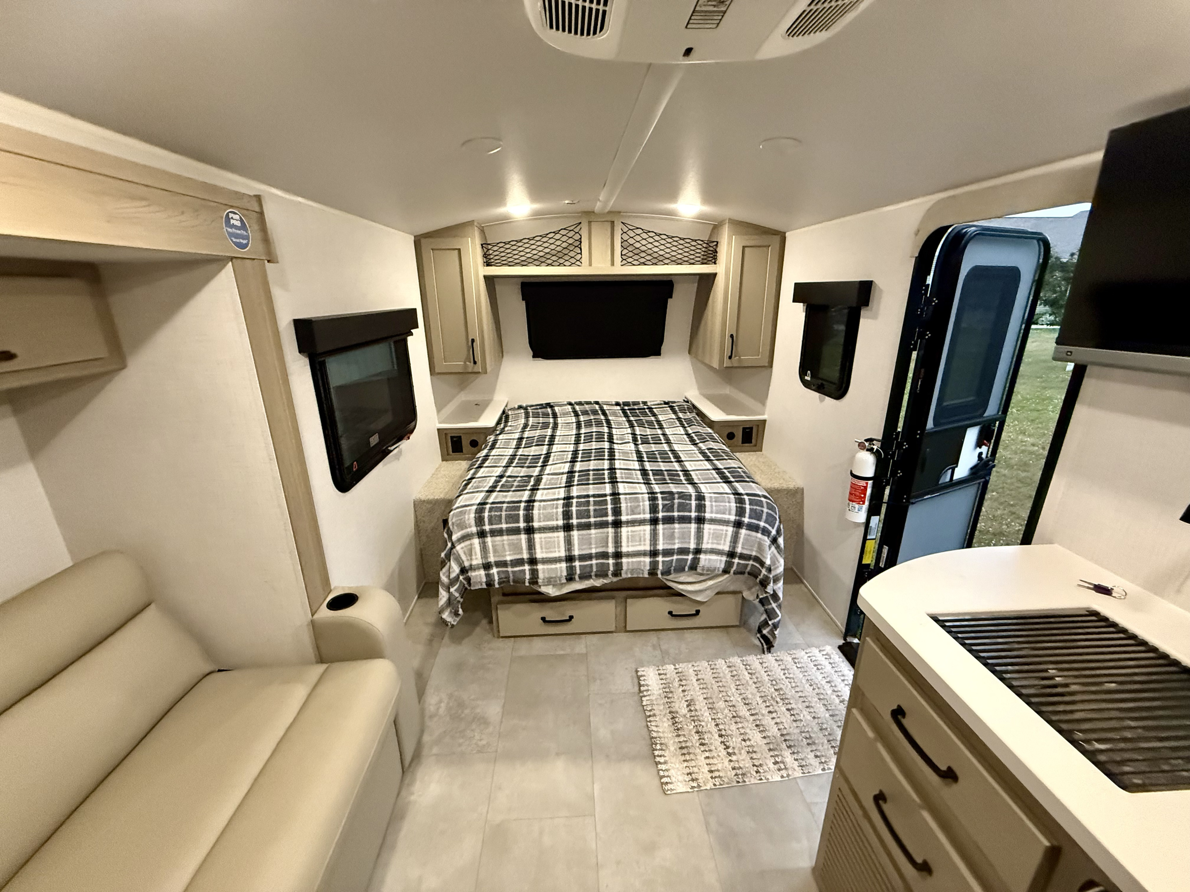 This compact RV rental interior features a comfortable bed, seating, and a small kitchen area, ideal for travel.. Forest River Rockwood Geo Pro 2025