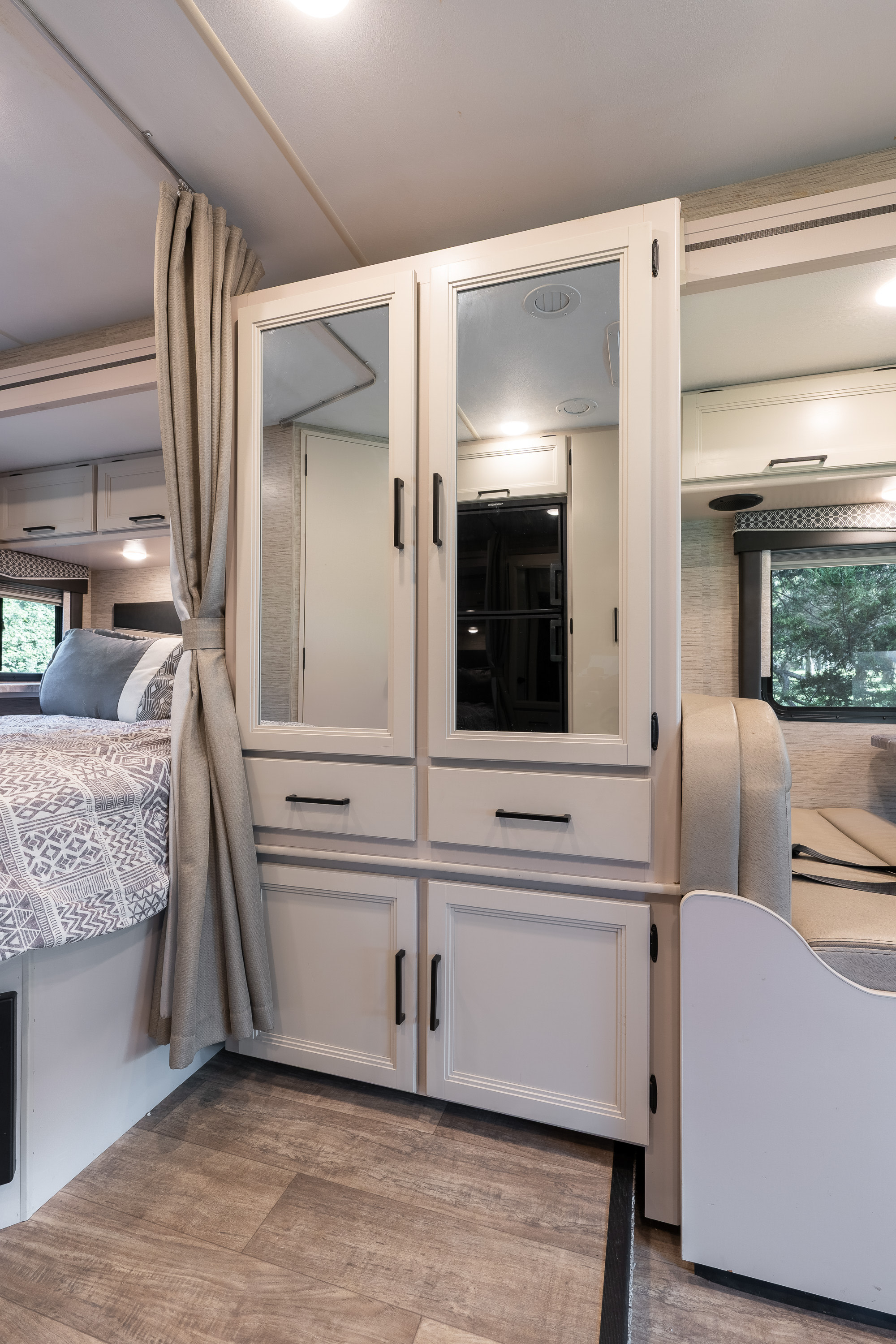 Inside an RV rental, featuring a bed, mirrored wardrobe, and dinette seating. A compact, well-designed living space.. Thor Chateau 2023