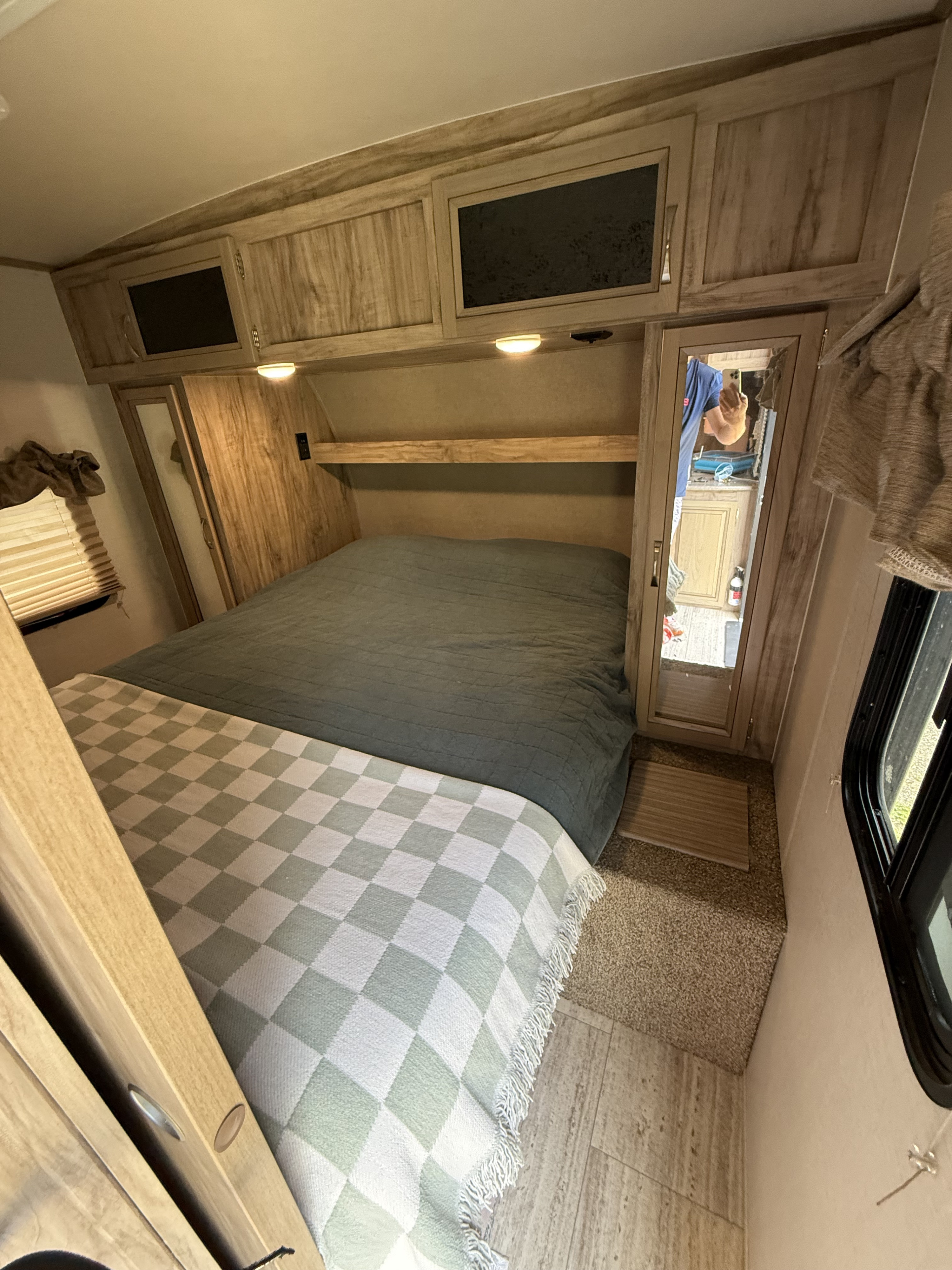RV rental bedroom interior, showing a comfortable bed with a checkered throw, built-in cabinets, and mirrored closet.. Palomino Solaire 240BHS 2018