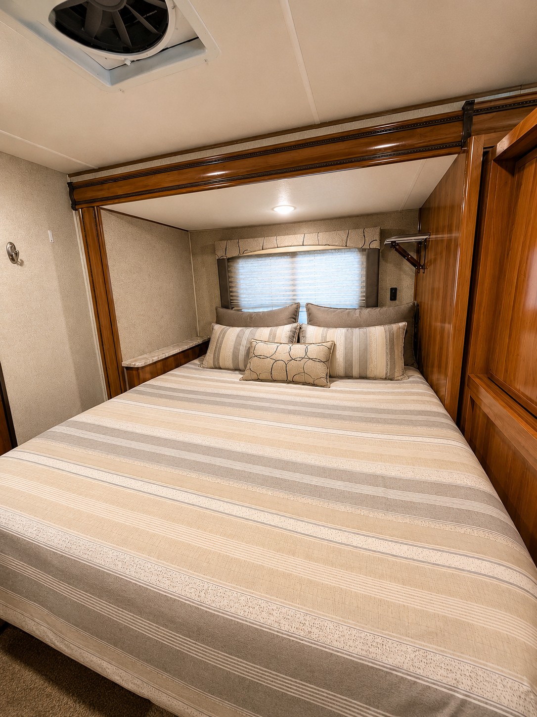 Enjoy a comfortable rv rental bedroom featuring a striped bed, window with blinds, and ceiling vent for fresh air.. Coachmen 240 2018