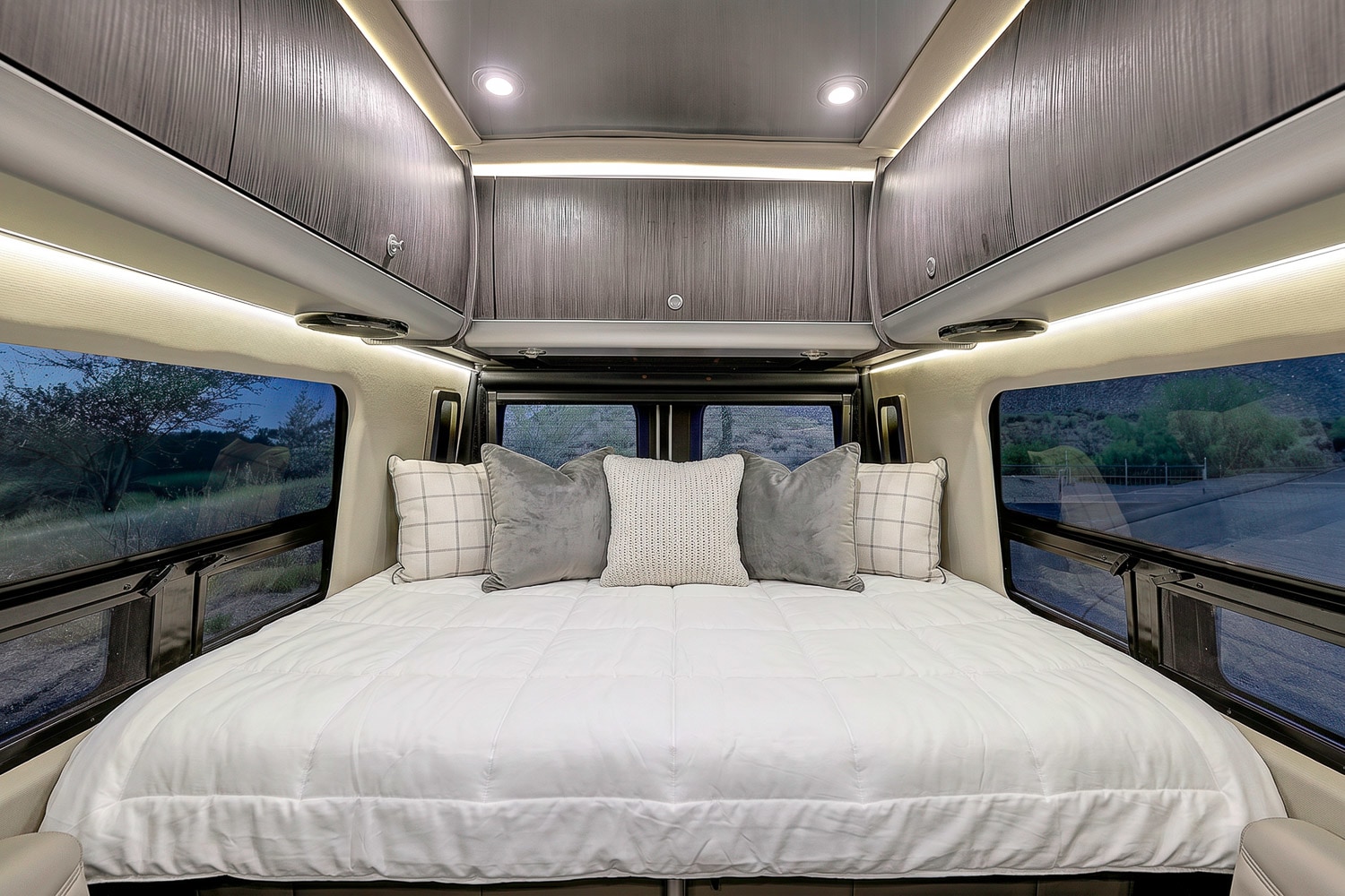 Inviting rv rental camper van bedroom with a large bed, cozy pillows, ambient lighting, and scenic night views.. Airstream Interstate 2021