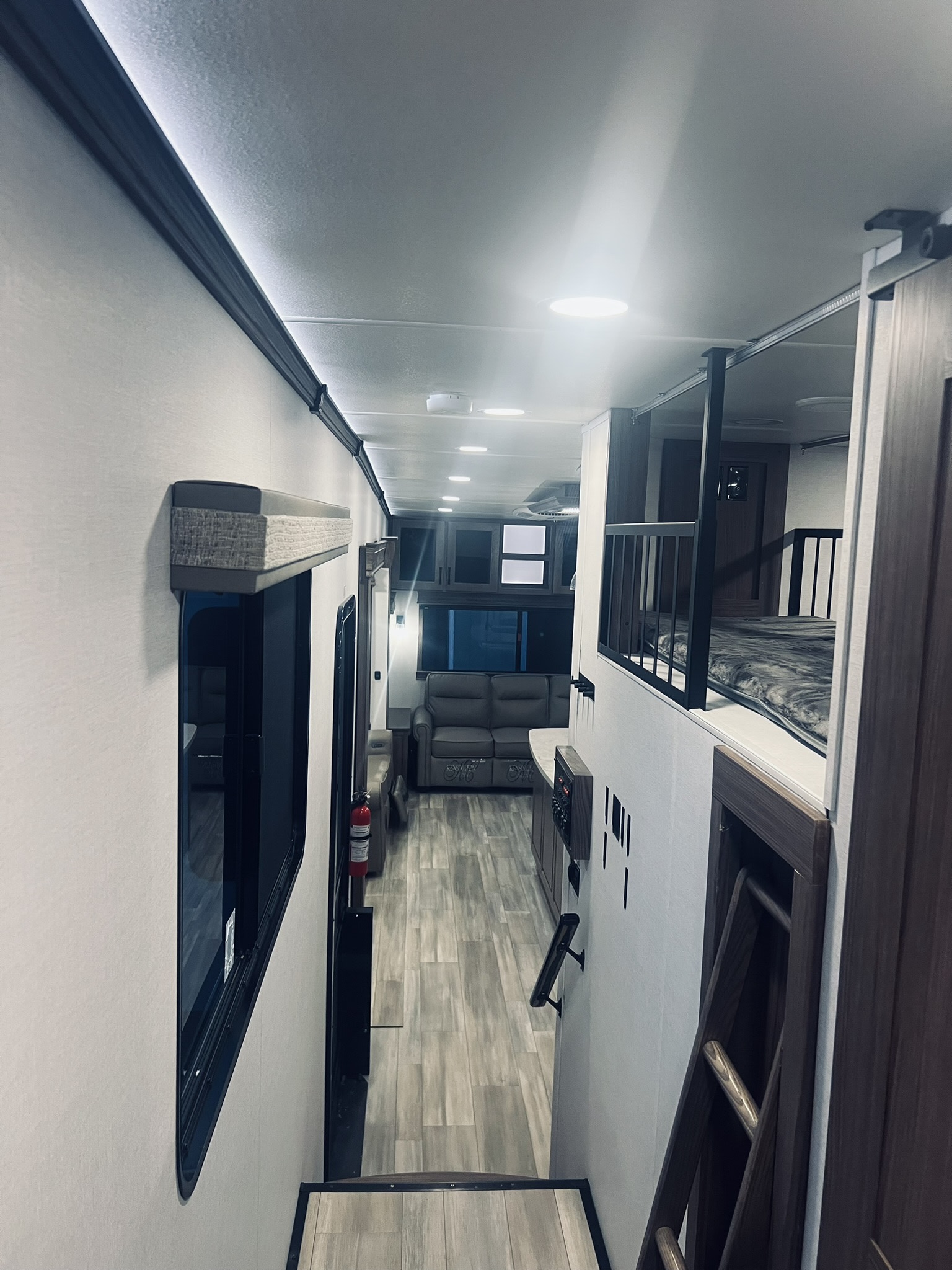 Spacious RV rental interior with a cozy loft bed, modern living area, and long hallway. Perfect for adventure!. Alliance RV Paradigm 2024