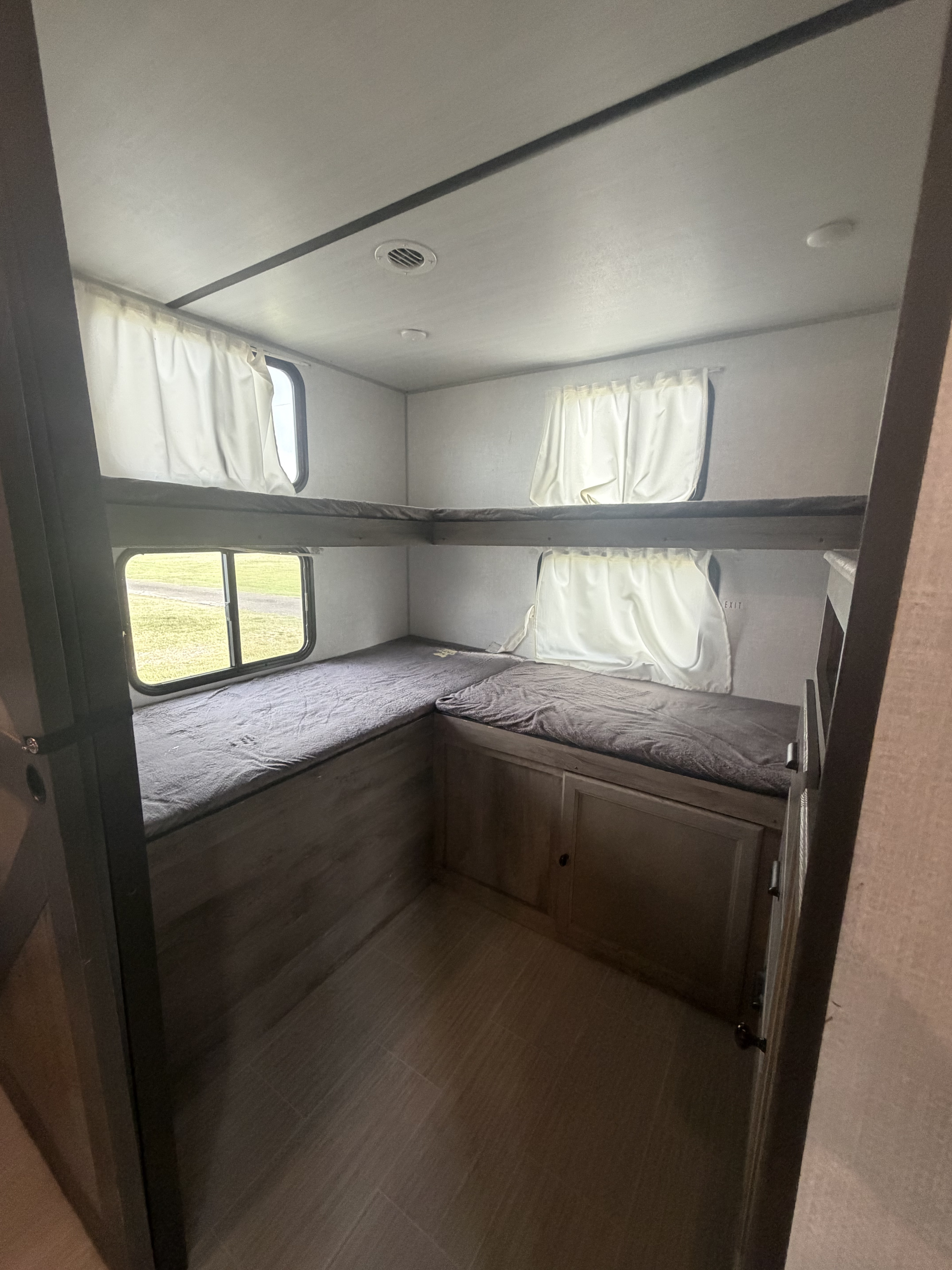 Comfortable bunk beds in this RV rental, perfect for family sleeping with storage below and windows for views.. Forest River Surveyor Legend 2021