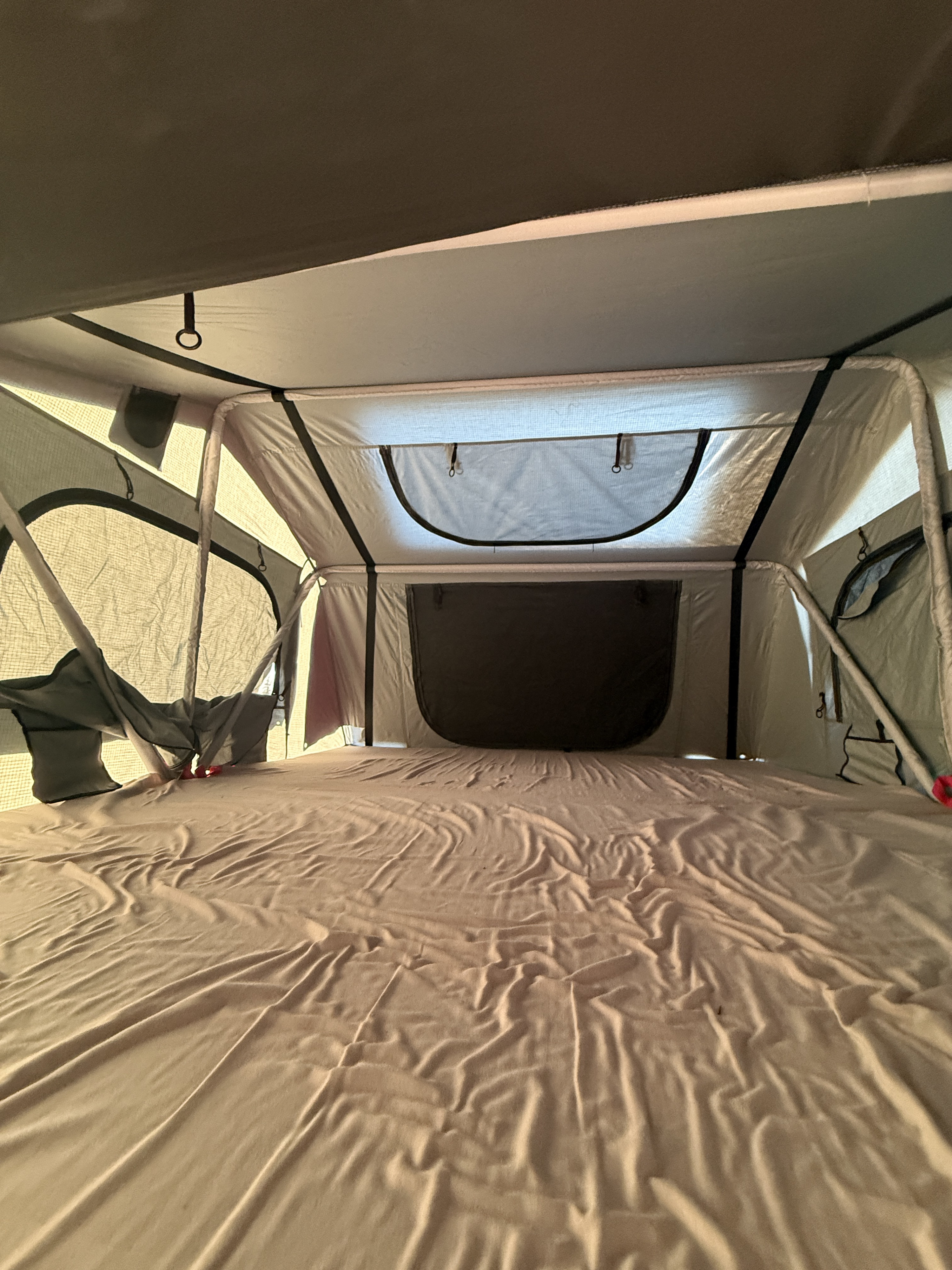 Inside a spacious RV rental rooftop tent, featuring a large mattress and airy windows. Ideal for comfortable outdoor sleeping.. Ford Ford F150 2018