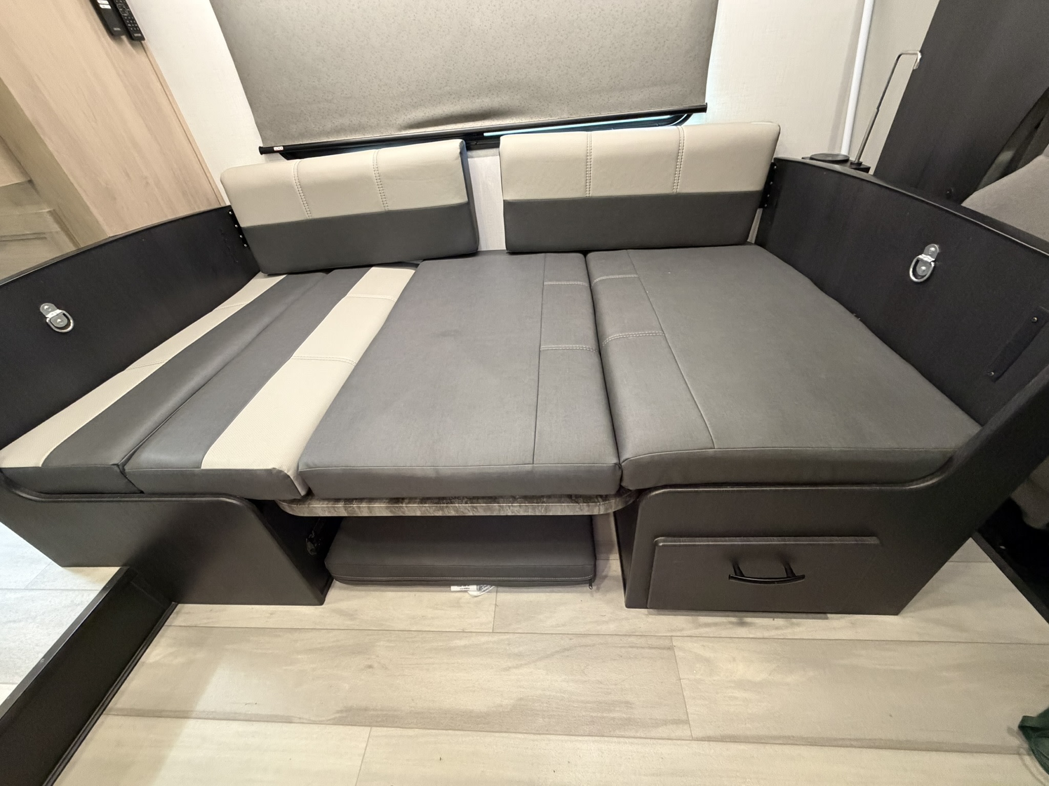 This RV rental features a versatile dinette area, convertible into a bed, with two-tone gray cushions and under-seat storage.. Forest River Sunseeker LE 2025