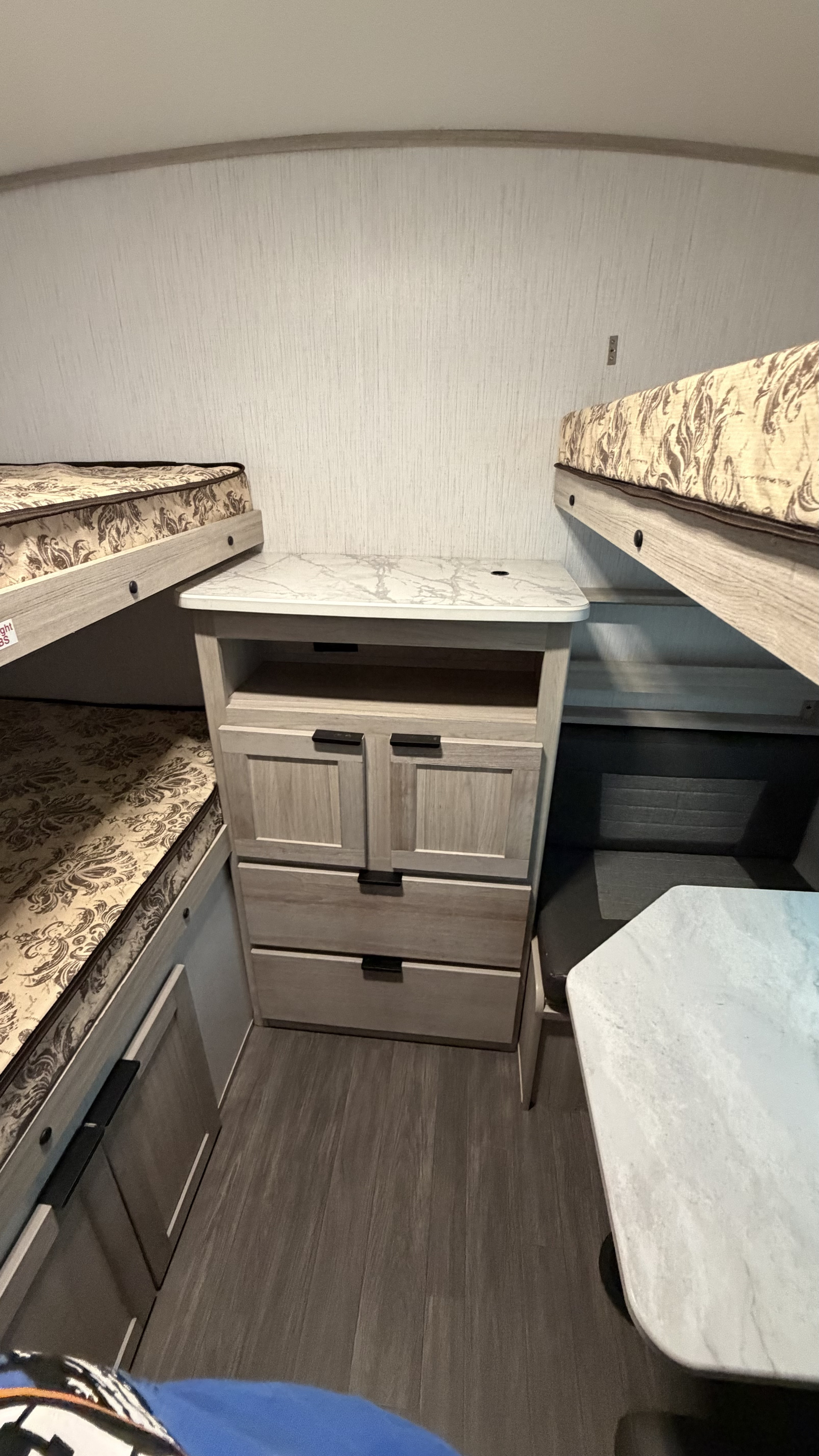 Cozy RV rental interior featuring bunk beds, a central dresser, and a compact dining setup with a light-colored table.. Cruiser RV Shadow Cruiser 2022