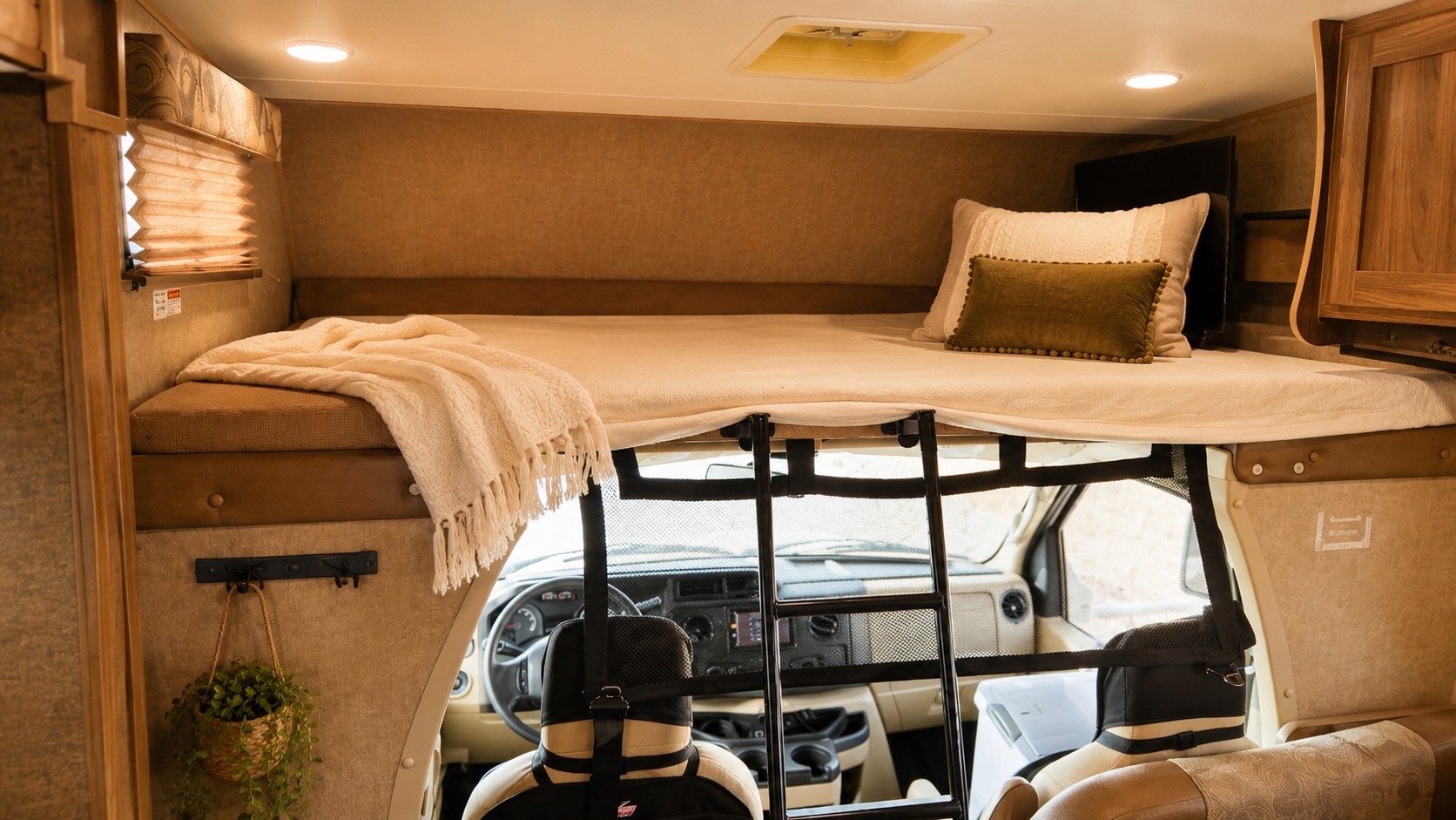 A comfortable rv rental interior: the elevated cabover bunk bed with a ladder, cozy bedding, and a TV overlooks the driver's cab.. Coachman Freelander 2016
