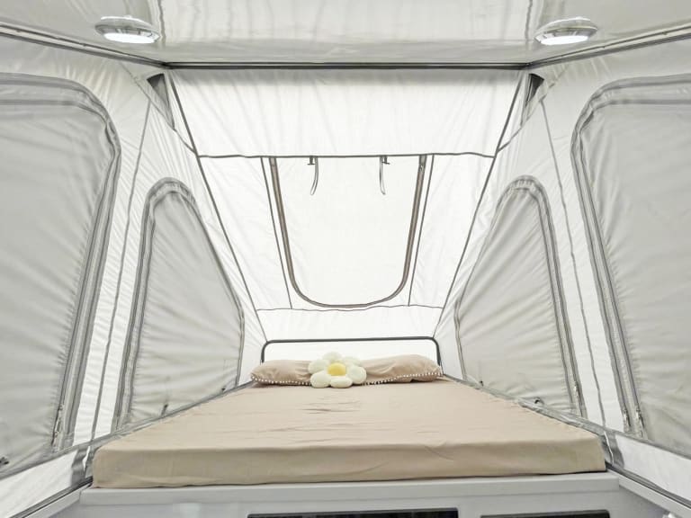 Experience comfort in your RV rental's sleeping area. This pop-up tent features a cozy bed, lights, and mesh windows.. Zoomies Campers Spirit 2025