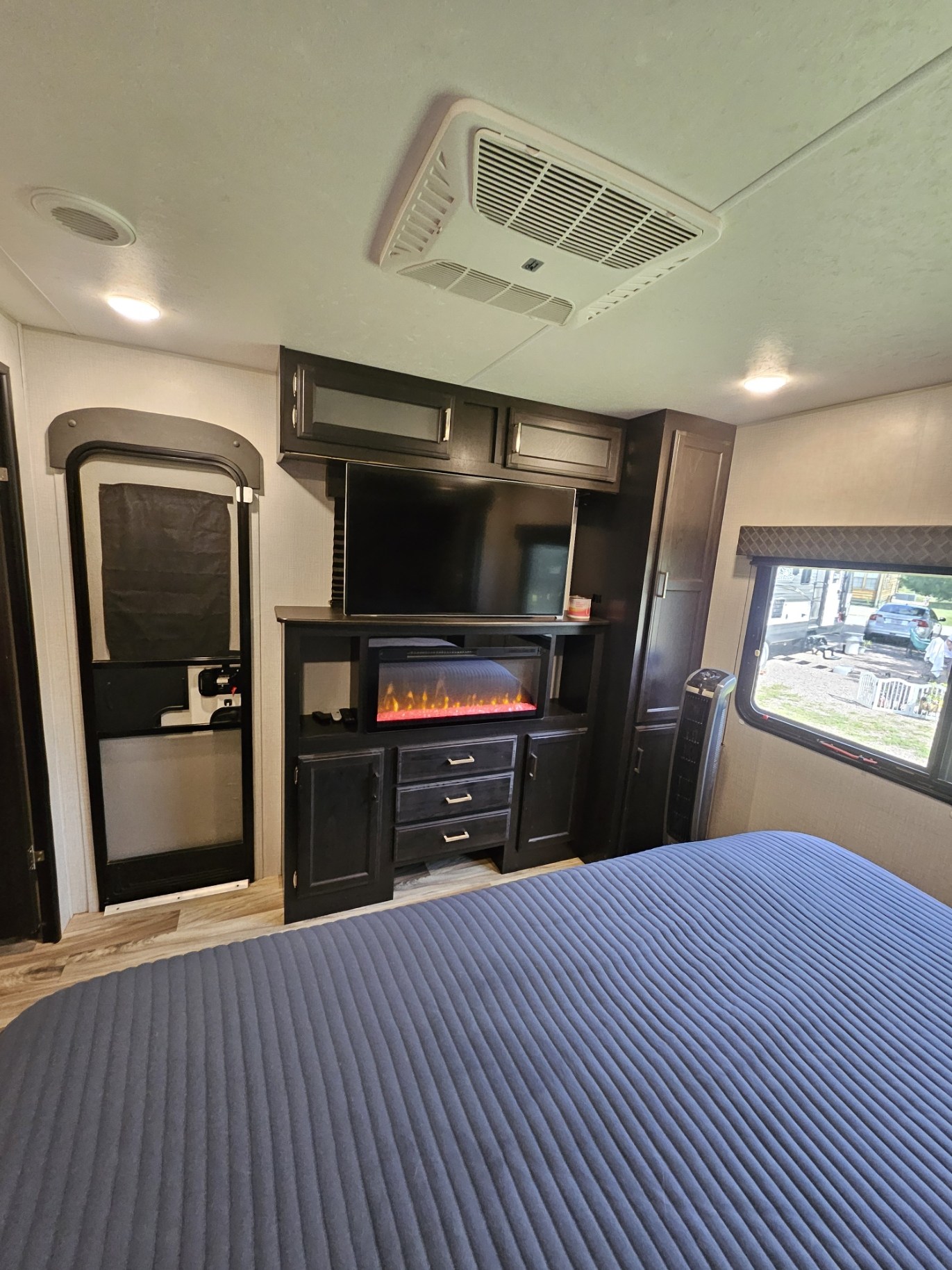 Cozy RV rental bedroom featuring a comfy blue bed, TV, electric fireplace, and storage for a pleasant stay.. Venture SportTrek Touring STT333VFK 2020