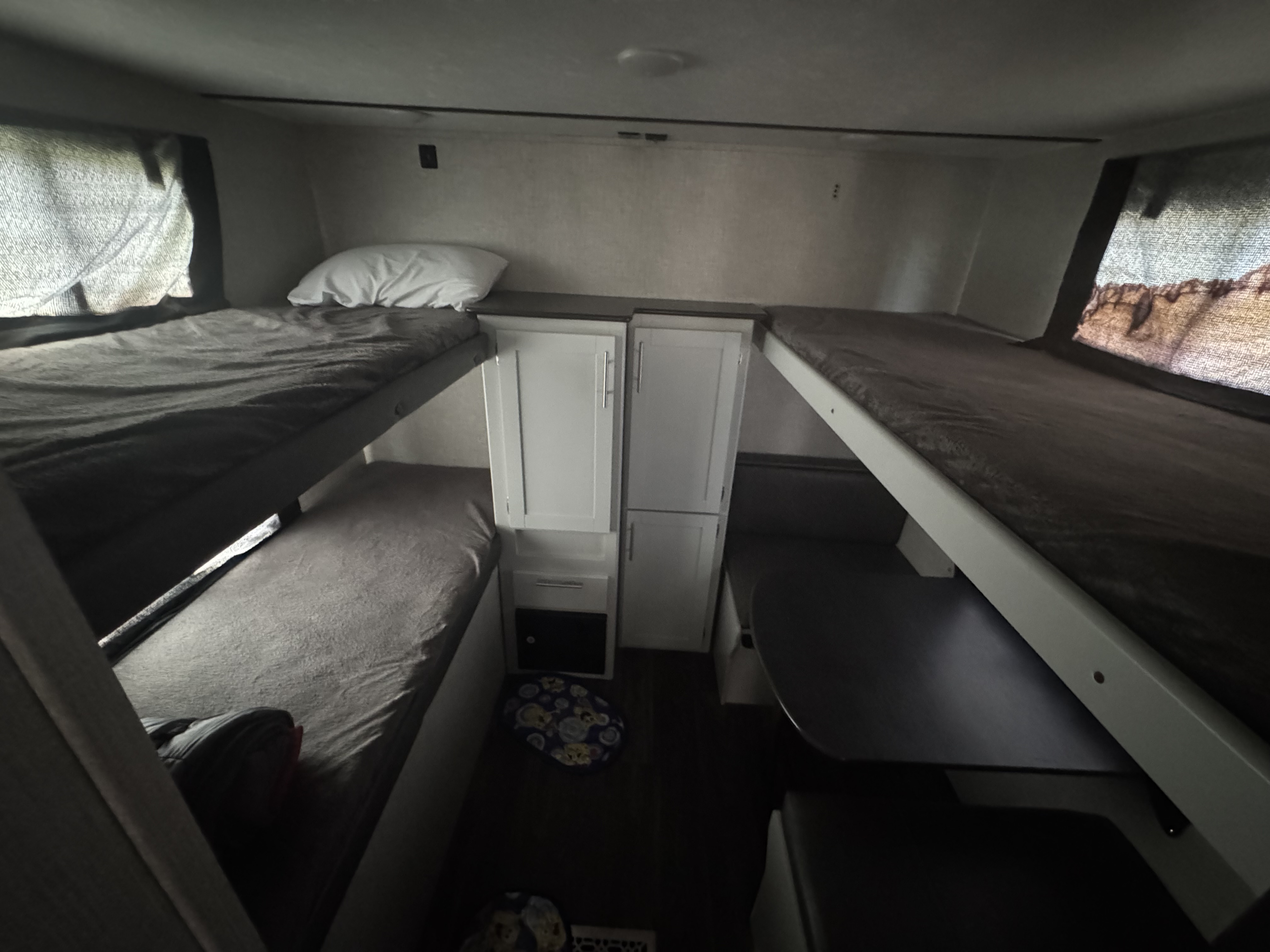 Cozy RV rental interior featuring bunk beds, a dinette, and storage cabinets. Ideal for compact family travel.. Keystone RV Bullet Ultra Lite 2021