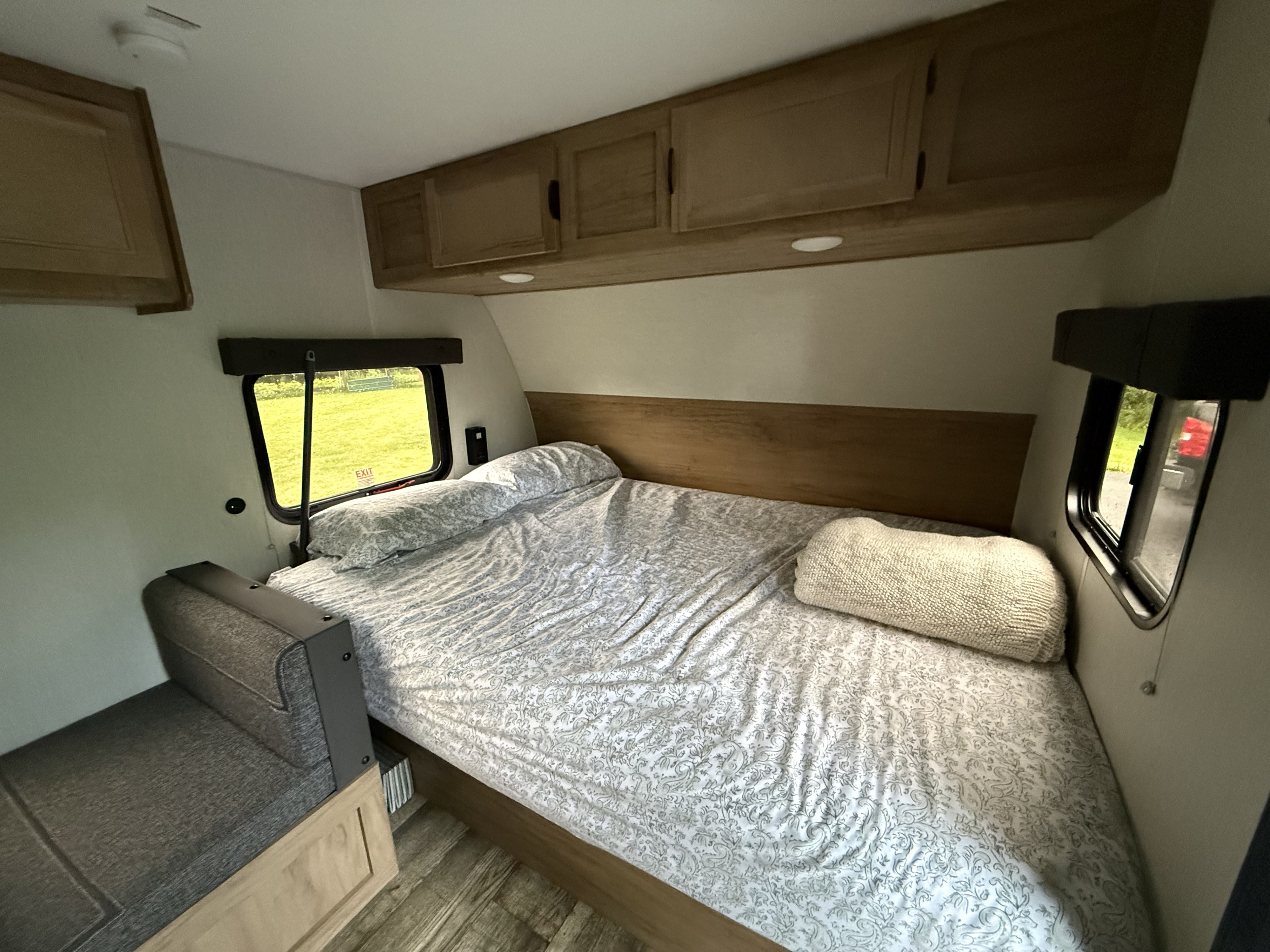 Inviting RV rental bedroom with a comfortable bed, overhead cabinets, and compact seating. Perfect for your next adventure.. Forest River Cherokee Wolf Pup 2024