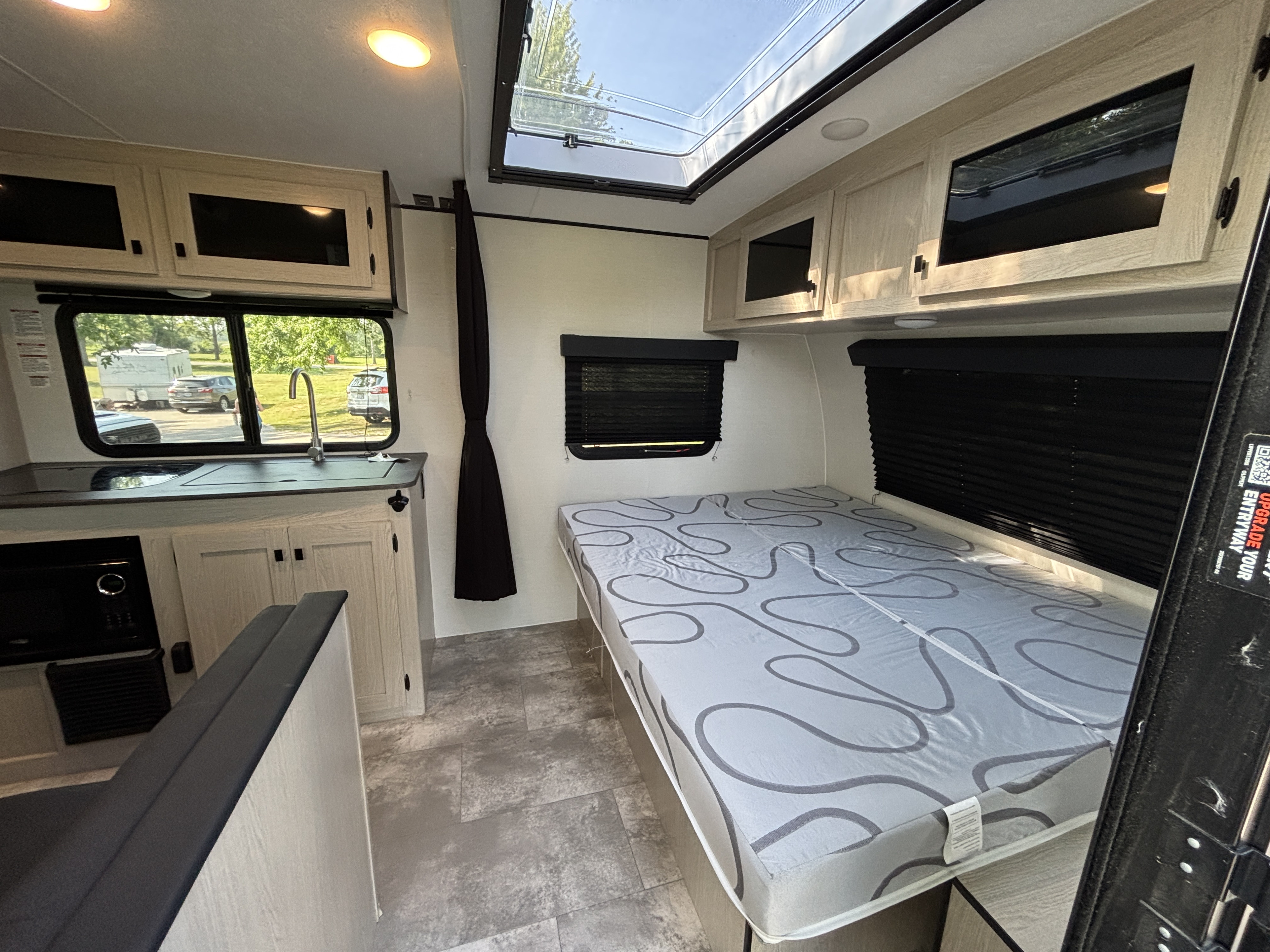 Cozy RV rental interior with kitchen, bed, and skylight. Bright and modern camper setup for your next adventure.. Coachmen Apex Nano 2024