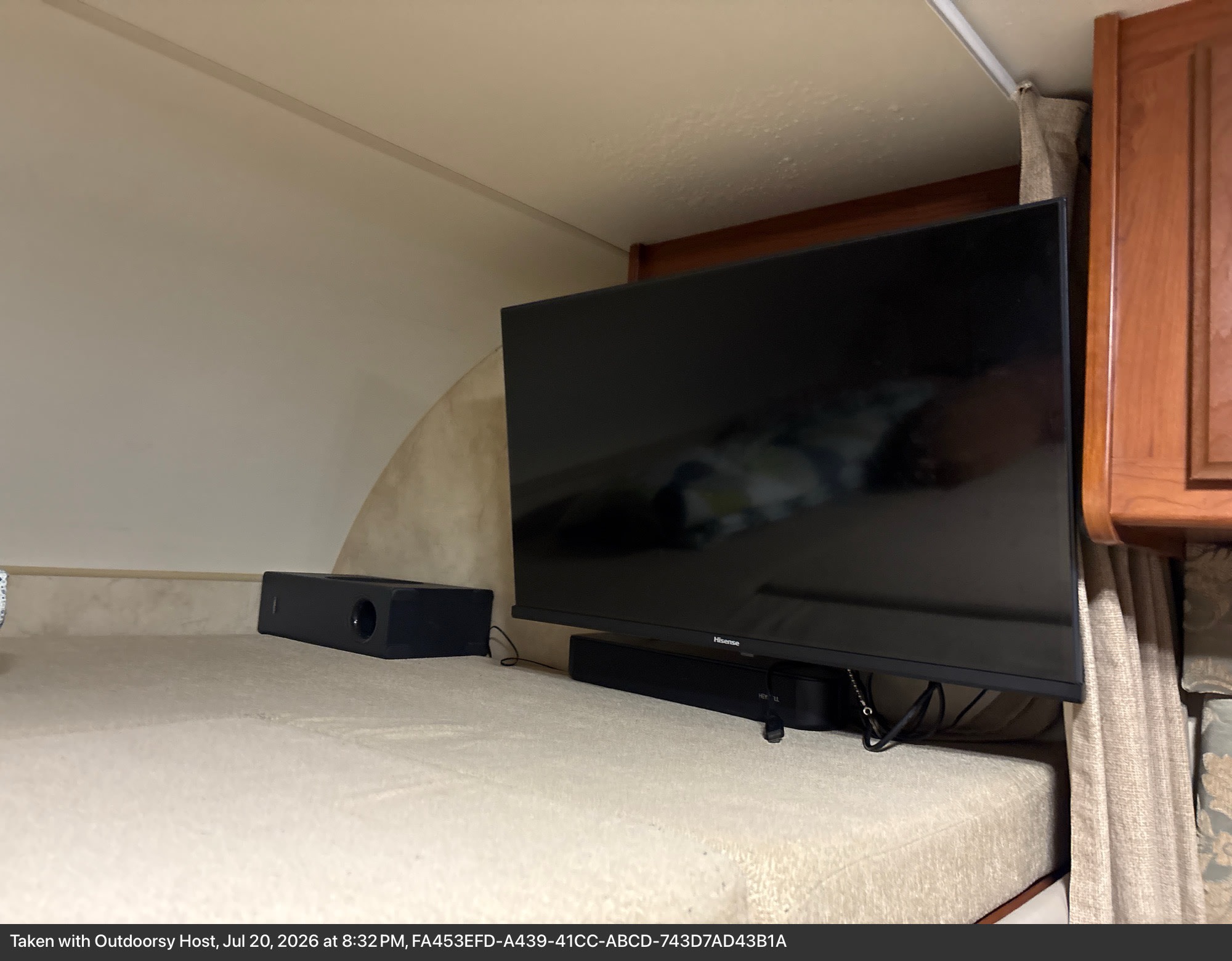 Inside an RV rental: a Hisense TV, soundbar, and speaker provide entertainment from a platform next to the comfortable bed area.. Thor Freedom Elite 2013