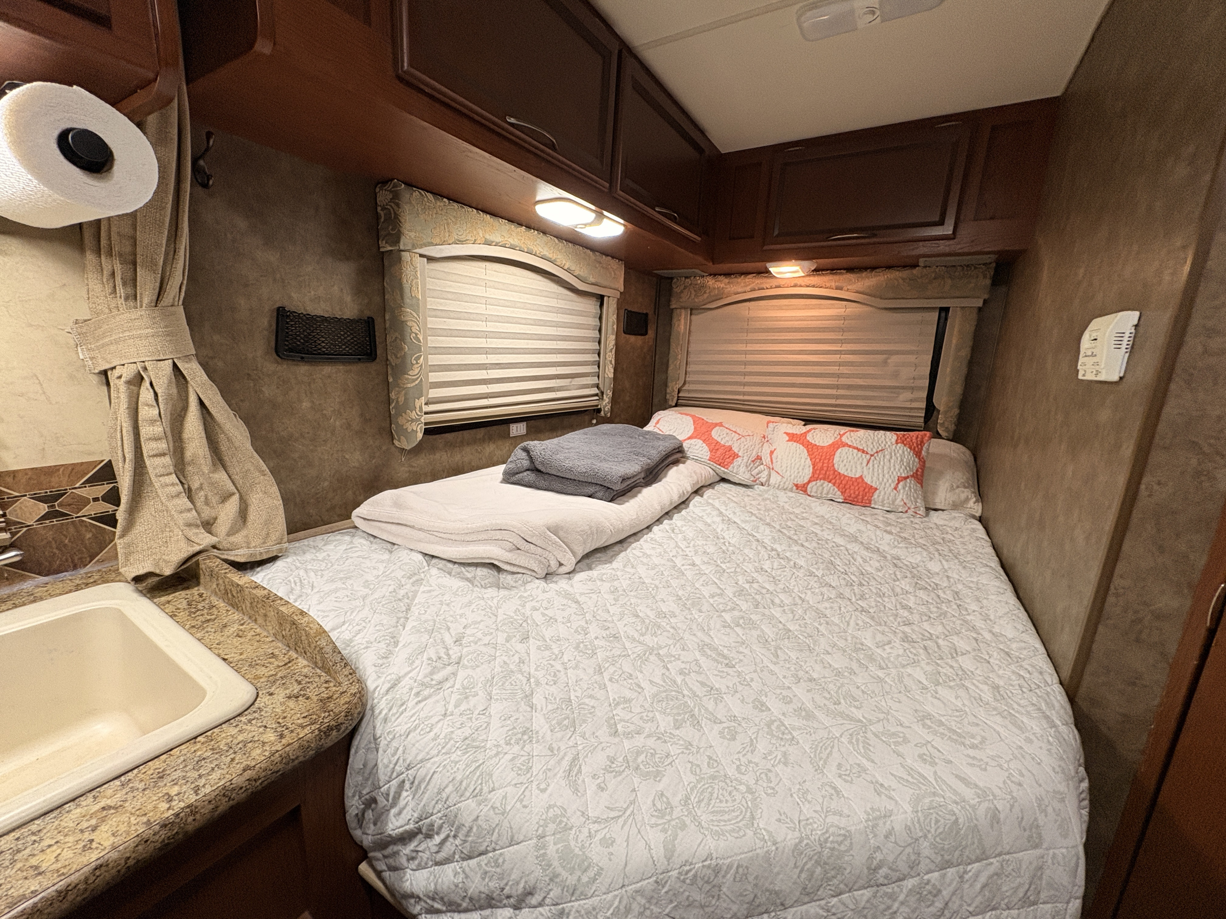 RV rental bedroom: a cozy retreat with a bed, storage, mini sink, and window blinds for travel.. Thor Freedom Elite 2013