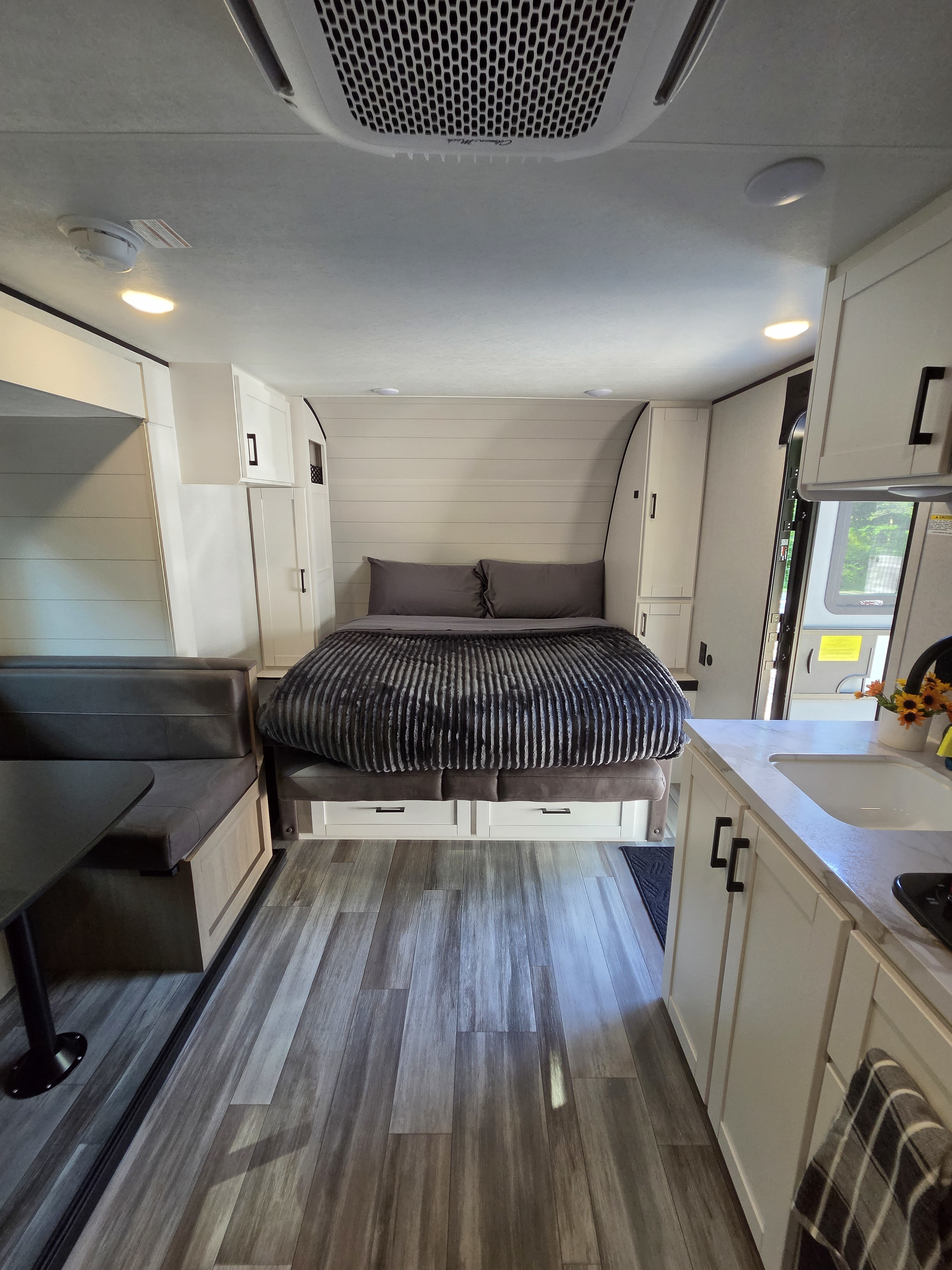 Modern RV rental interior showing a comfortable bedroom, compact kitchen, and dining booth with wood-look flooring.. Jayco Jay Flight SLX 2026