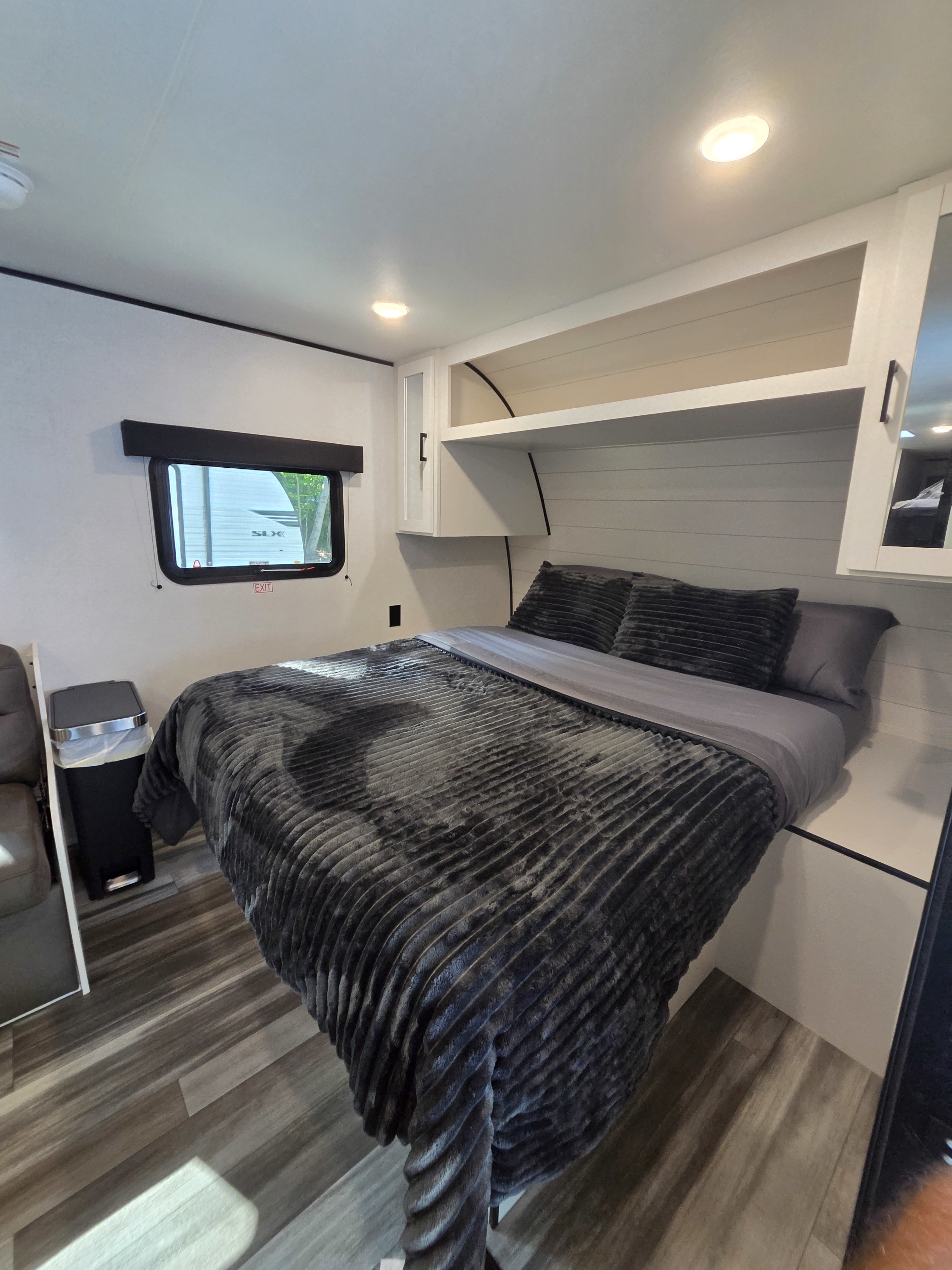 This RV rental offers a compact yet comfy bedroom with a plush gray bed, overhead cabinets, and a window for natural light.. Jayco Jay Flight SLX Sport Edition 2026